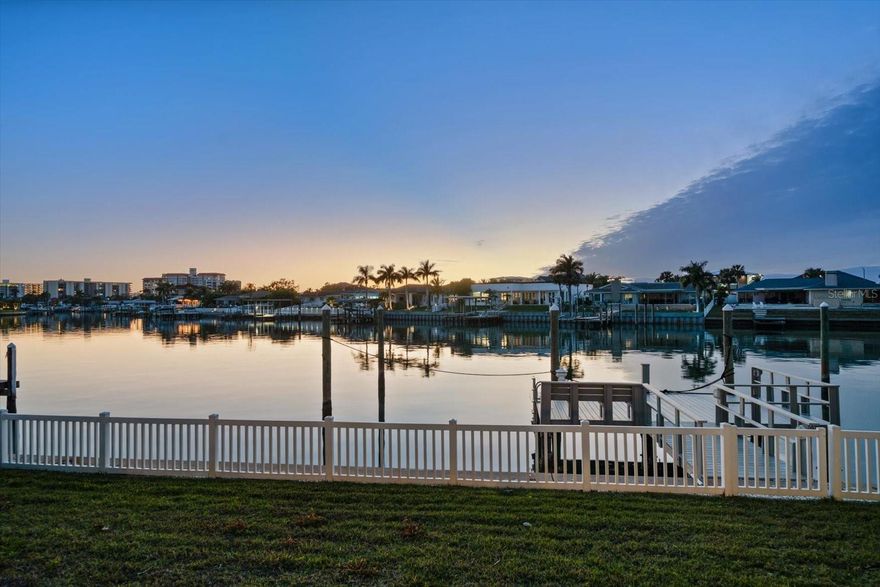 Set within the coveted Island Estates community, this waterfront residence presents an exceptional opportunity to reimagine coastal living in one of the area’s most sought-after enclaves. Offering a generously proportioned and well-designed floor plan, the home provides an impressive sense of space and flow—an ideal foundation for thoughtful updates and customization. A sweeping circular drive and stately double front doors create a grand first impression, opening to an interior where expansive water views immediately command attention. The main living areas are thoughtfully oriented to capture stunning, wide-ranging water vistas, filling the formal living and dining rooms with natural light and creating a seamless connection to the waterfront setting. The centrally located kitchen anchors the home and offers outstanding potential to be transformed into a true gathering space while remaining connected to the surrounding living areas. The primary suite is conveniently located downstairs, providing a private retreat with a walk-in closet and a spacious ensuite bath. Upstairs, three generously sized bedrooms offer flexibility for family, guests, or home office needs. Outdoors, relax poolside, enjoy a refreshing swim after a day on the water, or take advantage of easy access to the Intracoastal and the Gulf beyond. All of this is set within Island Estates, known for its distinctive waterfront lifestyle, boating culture, and proximity to beaches, dining, and shopping.