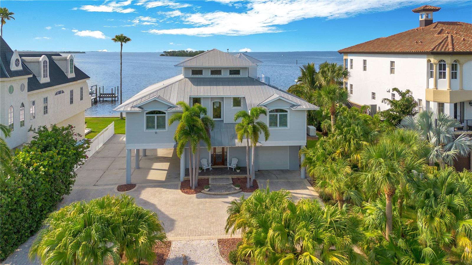 NO DAMAGE TO LIVING SPACE THROUGH BOTH HURRICANES! COVERED DOCK IN PERFECT SHAPE! Truly built correct! Come Discover one of the most extraordinary locations in North Pinellas County with this expansive double lot offering panoramic views of Honeymoon Island and Three Rooker Bar. Enjoy breathtaking sunsets each evening from the kitchen, living room, and master bedroom. The upper floor of this elevated home can serve as a separate in-law suite, complete with a living area, kitchenette, bedroom, bath, and air-conditioned storage.
Inside, the home is equipped with a central vacuum system, a Generac natural gas whole-house generator, and CCTV with monitors for enhanced security. The security alarm system and EV charging station add convenience and peace of mind. Elegant hardwood flooring throughout the home is complemented by a water softener for optimal water quality.
The property features an elevator providing access to all floors and includes custom storage cabinets in the three-car garage, with additional parking space available in the carport for three more vehicles.
Outside, the property boasts a covered boatlift and a 10’x 20’ dock. This property boasts a rare, separate front parcel that offers endless possibilities for customization and expansion. With direct open water access, this buildable lot currently features a private pickleball court, perfect for sports enthusiasts or those who love outdoor entertainment. Keep the existing pickleball court and add a guest house, creating the perfect retreat for visitors ! Alternatively, consider transforming the space with a large swimming pool, lush landscaping, or even a personal outdoor oasis. Whether you're looking to expand, entertain, or invest, this rare key lot sets this home apart from the rest, offering flexibility and unparalleled options. The location is ideal, with a short walk or boat ride to the marina for fuel, bait, and supplies, and close proximity to the Pinellas Trail, Honeymoon Island, Downtown Dunedin, and A-rated schools. Situated in the charming town of Ozona, this home is in the heart of Palm Harbor, surrounded by quaint shops and restaurants.