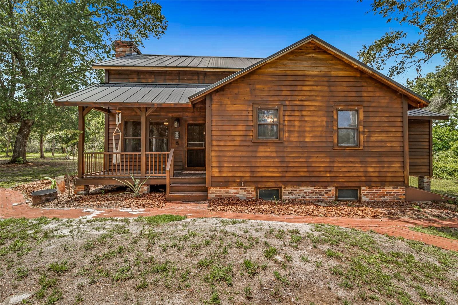 NEW METAL ROOF | NEW HVAC SYSTEM. Welcome to 42328 Dogwood Ave, a stunning 5-bedroom, 2-bathroom custom-built home on 5 high-and-dry acres in the peaceful countryside of DeLand, FL. Built in 2004, this 1,890 sq ft rustic retreat blends modern upgrades with timeless charm, offering space, privacy, and functionality for today’s discerning buyer. This move-in-ready home has been thoughtfully updated with a BRAND NEW HIDDEN FASTENER METAL ROOF, a NEW HEAT PUMP WATER HEATER, and TWO NEW 2-ton HVAC UNITS for superior energy efficiency and peace of mind. Inside, discover a bright, inviting layout with many NEW LIGHT FIXTURES , ceiling fans, an eat-in kitchen featuring a NEW BOSCH DISHWASHER, and a main-floor primary bedroom with walk-in closets and a newly renovated en suite showcasing a NEW VANITY, SINK, TOILET AND TUB. The laundry was conveniently moved from the basement to the first floor for added ease. The finished full basement offers four versatile rooms ideal for a home office, gym, or guest space.Step outside to relax on the expansive front and back porches, perfect for enjoying nature. The backyard includes a well-maintained above-ground pool with a new pool deck, and the land has been thoughtfully cleared for improved usability. The property also features a REMOTE CONTROLLED GATE OPENER for extra convenience and security. For hobbies or a home business, there’s a 2-story workshop/bonus building with a separate office entrance, plus two additional sheds and a detached 3-car garage with an enclosed carport and door openers, providing ample storage and parking space.Located just minutes from the St. Johns River, the Chain of Lakes, and Ocala National Forest, this home is a dream for outdoor enthusiasts, with quick access to boating, fishing, and trails. Downtown DeLand is only 15 minutes away, offering dining, shopping, medical facilities, and community events, while I-4 connects you easily to Orlando and Daytona Beach.Don’t miss this rare opportunity to own a fully upgraded DeLand gem. Contact us to schedule your private tour today!