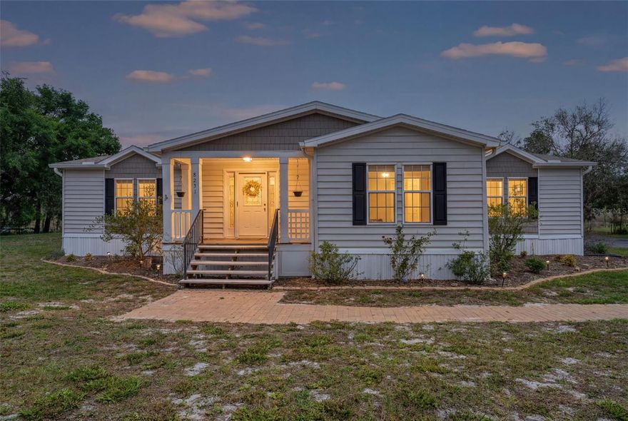 Welcome to this beautifully maintained 3-bedroom, 2-bath home situated on 1.09 acres in desirable Floral City. Located within Lake Magnolia Estates with no HOA or CDD fees, this property offers privacy, space, and direct lake frontage. A long, oversized driveway, perfect for boat or RV storage, leads to a neatly manicured entrance, setting the tone for the home’s inviting curb appeal. Walking up, take note of the adorable porch and smart doorbell. Inside, you’ll find over 2,170 square feet of living space featuring luxury vinyl plank flooring (2022), a light and bright entryway, and a well-designed, flowing floor plan. The updated kitchen (2022) is a standout, showcasing white shaker soft-close cabinetry with crown molding and a pantry-- with pull out drawers, glass-front display cabinets, built-in plate storage, granite countertops, a farmhouse sink, newer stainless steel appliances - including a double oven (2022), and a new dishwasher (2025). The adjacent formal dining area connects seamlessly to the open living room, which features crown molding, tray ceilings and sliding glass doors leading to the Florida room—perfect for entertaining or enjoying indoor/outdoor living. The split floor plan provides added privacy, with the spacious owner’s suite tucked away on one side of the home. It includes a walk-in closet with built-in shelving and a fully updated ensuite bathroom (2022) featuring a freestanding soaking tub, tiled walk-in shower, dual vanities, and a private water closet. On the opposite side of the home, you’ll find an open office area, two additional bedrooms with ample closet space, and a beautifully updated guest bathroom (2022) with a tub/shower combination. Enjoy Florida living outdoors with a large screened lanai (20x18) with vinyl windows (2015), an oversized wood sun deck, and an attached 2-car carport. The elevated positioning of the home adds extra peace of mind. Additional highlights include a detached 24x26 two-car storage building with electric, a perfect space for a workshop or extra storage, as well as an additional shed for lawn equipment or recreational items. Recent updates include a new roof (2024), interior paint and lighting (2022), water heater (2020), AC (2018), a raised well with a new tank (2022) and new washer and dryer (2026). There is also a full home water softener with an iron filtration system! Outback there is a fire pit and plenty of space to grow and enjoy! This home is a 41 x 70 triple wide by Southern Energy Homes and will not last long, centrally located near the Floral City historic district, close to amenities, eateries and all Florida has to offer, make your appointment today!