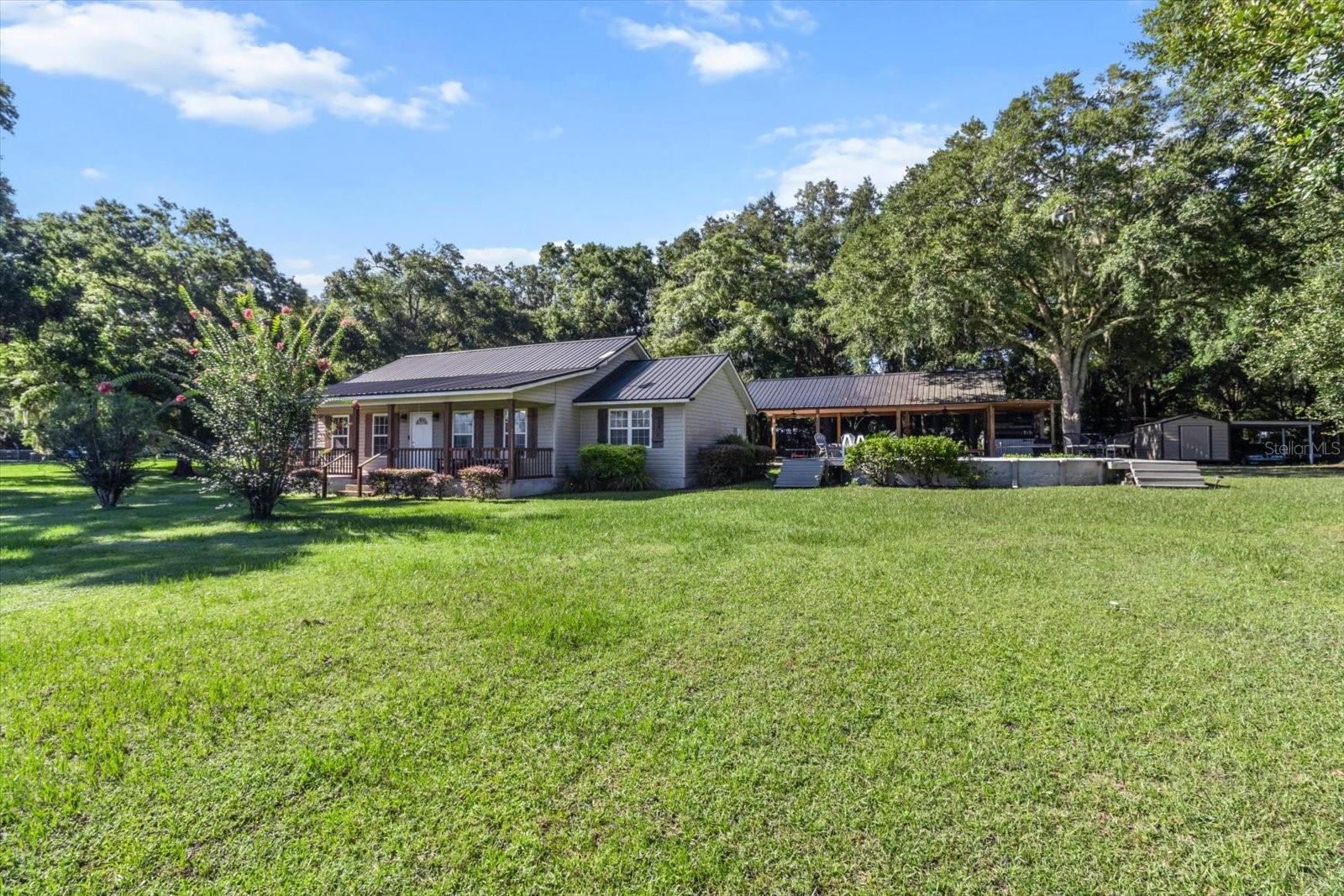 Welcome to your dream farmhouse retreat! Situated on 5 fully fenced acres with mature trees and plenty of open space, this beautifully updated 3-bedroom, 2-bath modern farmhouse offers nearly 2,200 square feet of stylish and functional living. Inside, you'll find an open floor plan with vaulted ceilings, crown molding throughout, and a stunning shiplap fireplace anchoring the great room. The family room features charming tongue-and-groove ceiling and wall accents, adding to the home’s cozy character.
The large kitchen is a showstopper with granite countertops, tile backsplash, stainless steel appliances, a farmhouse apron sink, breakfast bar, and eat-in space — perfect for gatherings and everyday living. The spacious primary suite offers dual vanities, a walk-in shower, and a huge walk-in closet. Guest bedrooms are generously sized, and there’s even a dedicated office/flex room to suit your needs.
Outdoors, enjoy the pool, a welcoming front porch, and a fully equipped outdoor kitchen with an entertainment area — ideal for relaxing or hosting guests. The entire property is fenced and includes a dog run. Zoning allows for up to 5 horses and 5 colts, and one home an acre can be built, making this an excellent opportunity for expansion or multi-home living. With no HOA, you can bring your boats, tractors, four-wheelers, and more. Metal roof, tile/wood flooring throughout (no carpet), and timeless modern farmhouse style complete the package. This is a rare opportunity to live the country lifestyle without sacrificing comfort or style!