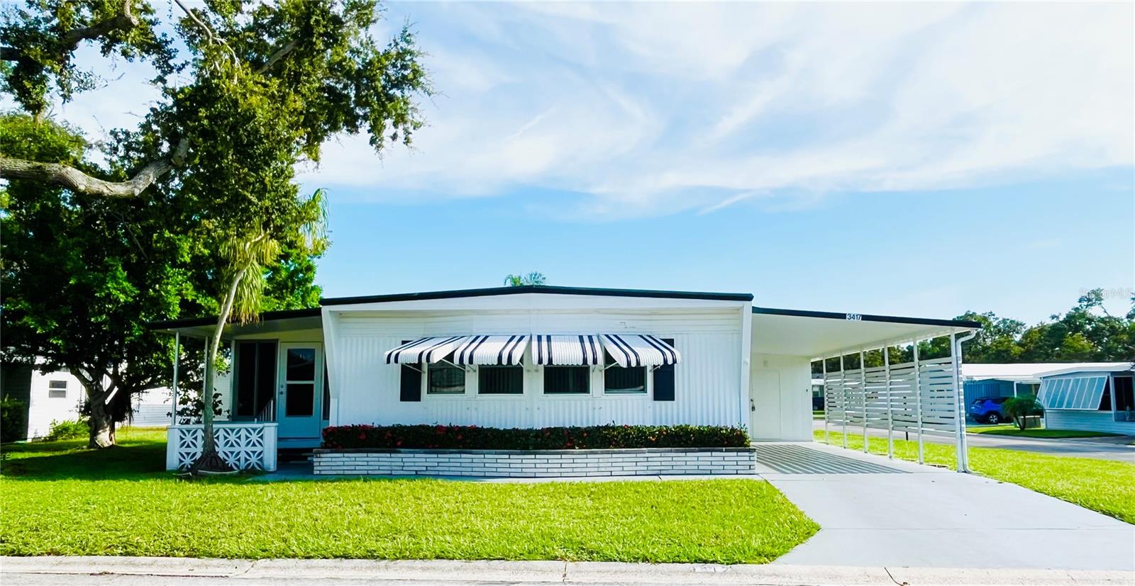 What a deal for this fantastic oversized corner lot home - Located in the ONLY Resident Owned Park in the City limits of Sarasota!!
This 2 bed 2 bath home really does feel like a private oasis with no homes on 2 sides and trees giving shade and privacy on the Florida room side. The spacious living room is just off the main dining area where wall to wall storage and a buffet top give added entertaining space for the dining room. Just off the living and dining is a 200sf enclosed Florida room with wall to wall plexi insert slide windows that can be opened or removed to enjoy those cool breezy days and this space can be easily turned into an all season room giving additional living and sleeping for guest. Off the Florida room there is an exit door that leads to a quaint front covered patio space. The primary bedroom has an en-suite bath with an updated step in shower and the guest bath features a tub/shower and is located just off the hall from the guest bedroom and main area to the home. The carport has privacy slats that also help keep the morning sun off the cars. Most rooms have their own built in wall heat for those chilly winter days. The Washer/Dryer are located in the shed.
Updates: Membrane roof over age ?, Double pane windows, plumbing has been updated and has shut offs, emergency electric was added 2003. Hurricane shutters.
The gated 90 acre community boasts a low maintenance fee with its vast amenities starting with the spacious Clubhouse outfitted with a full commercial cook kitchen, event stage, audio/visual, dance floor, state of the art fitness room, activities hall, library with books/movies/puzzles and a pool table. Outside recreation includes an extra large heated pool with a handicap ramp, a spacious kidney shaped hot tub, ample umbrella tables and lounge chairs and updated shower rooms. Oak trees shade the beautiful park area, picnic tables and a community grill. Additional amenities to enjoy are the community putt putt course, bocce ball, ping pong, horseshoes and corn hole. Oakwood Manor is a vibrant community with numerous social events and activities. Conveniently located adjacent to Legacy Trail and 12 newer pickle ball courts. Just a short drive to our crystal sand beaches, downtown area, the marina, fishing pier, local golf courses, shopping, variety of restaurants, the museum, SRQ airport, SMH and Doctors hospitals. Please note that Oakwood is a 55+, no pet, no motorcycle Park.