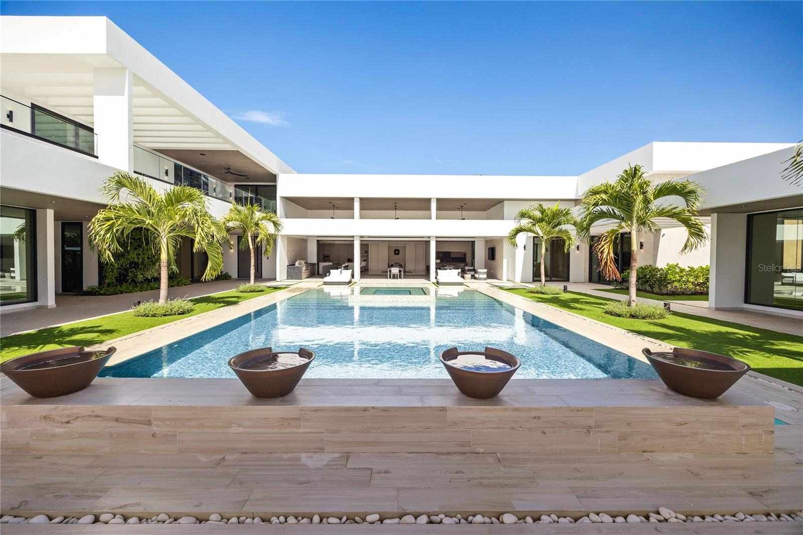 Dorado Country Estates - A Boutique Hotel-Inspired Property
Step into one of the most extraordinary properties at Dorado Country Estates, a home that redefines luxurious living with the ambiance of a boutique hotel. At its heart lies a stunning interior courtyard featuring a vertical plant wall, a serene waterfall jacuzzi, and a sparkling pool, allowing abundant natural light to flood nearly every room. Thoughtfully designed with unparalleled attention to detail, this estate offers 6 spacious bedrooms, each with ensuite bathrooms. Two downstairs guest suites stand out with their own separate entrances, private kitchenettes, and direct access to the pool, creating the ultimate retreat for visitors or multi-generational living. The master suite is a private oasis, complete with a spa-like bathroom featuring dual showers and a soaking tub, an oversized closet with a center island, and an adjacent private office. The great room flows seamlessly into a chef’s kitchen outfitted with dual islands, Sub-Zero and Wolf appliances, a wine fridge, and a pantry. This space opens to a covered terrace equipped with an outdoor kitchen and living area, perfect for entertaining.
The home is equipped with premium upgrades throughout, including a Culligan water softener, ceiling speakers, sound bars, and subwoofers for an immersive audio experience. Doors and windows by Alumni from the Durabella Group combine elegance with durability. The property’s thoughtful infrastructure includes an 800-gallon cistern and a 300-gallon irrigation system to support sustainable water management. The upper level feels like a home within a home, featuring three additional bedrooms, a family room, a second laundry room, and two terraces—one covered with views of the courtyard and another open-air terrace overlooking the surrounding mountains. Designed for relaxation and entertaining, the outdoor spaces include expansive covered terraces, a large pool, a convenient pool bath, and an outdoor shower nestled within lush landscaping on a 2,500-square-meter (26,909 sq. ft.) lot. A three-car garage with a golf cart bay and extra storage completes the home. This exquisite property is more than just a residence—it’s a luxurious sanctuary designed for family connection and entertaining on the beautiful island of Puerto Rico