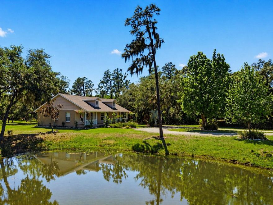 Set on a private, pie-shaped 7.95-acre lot, In Winding Creek, that stretches deep into the lush wooded forest, this partially fenced estate offers a rare combination of usable land, natural beauty, and thoughtful improvements. The grounds feature a private fishable pond, expansive cleared areas for recreation, and wooded sections that create privacy, including a charming enclosed treehouse with deck. The home is complemented by a detached two-story carport offering two oversized covered parking area and two heated and cooled rooms (one upstairs and one downstairs, not included in the published sq/ft), ideal for an air-conditioned workshop, hobby space, or guest overflow. Additional exterior highlights include a well-maintained and covered well system with pump, bladder tank, and filtration, a huge circular driveway, irrigation system, and beautifully manicured front and rear lawns with lush landscaping. Inside, the open floorplan features vaulted ceilings throughout the main living areas, a spacious living room with a wood-burning fireplace, and a kitchen with stainless steel appliances, breakfast bar seating, and a large dining area. The home offers three bedrooms and two fully updated bathrooms, along with an inside laundry room complete with washer, dryer, second refrigerator, and side entry access. Flooring includes hardwood and tile throughout the main living areas, bathrooms, and primary suite, with wood laminate in the secondary bedrooms. Enjoy outdoor living year-round from the 12x24 covered and screened rear patio with double door access from both the living room and primary bedroom. With a new roof in 2024 and a property that balances open space and wooded privacy, this is a truly unique opportunity to own nearly 8 acres with exceptional features and flexibility.  Winding Creek is a private, nature-surrounded community featuring an equestrian center and expansive common areas ideal for walking, hiking, biking, and horseback riding, conveniently located approximately 20 minutes east of I-75 off SR 64.