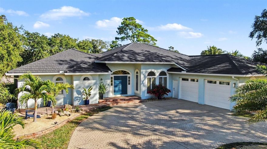 Luxury coastal living on 1-acre + a boat slip in Merritt Island. This home has it all: 4 beds, 4 full baths, a huge circular driveway, a pool, and an 864 sq ft garage. Soaring 14 & 10 ft ceilings throughout, abundant natural light, and a statement fireplace. A new metal roof (2025), gutters, and solar attic fans are just the first of many updates. Wide plank luxury vinyl flooring, stylish kitchen and baths, and LED lighting in every room create a spacious entertaining showcase. Completely redone low-maintenance tropical landscaping and stunning 40-year-old oak trees create a private, shaded oasis in the front and back fenced yards. Enjoy a private screened pool and deck, making entertaining a breeze. You'll love the spacious master suite featuring a coastal vibe, en suite bath, new double vanity, sconce lighting, and two huge walk-in closets. This home has exclusive use of slip #7 in the community marina, with its own private 8,000-lb boat lift (new 2022), providing direct access to the river/ICW.  An extra-long 864 SF garage includes two bays plus bonus space. A rare blend of acreage, updates, garage space, and premier boating access is ready to be yours.