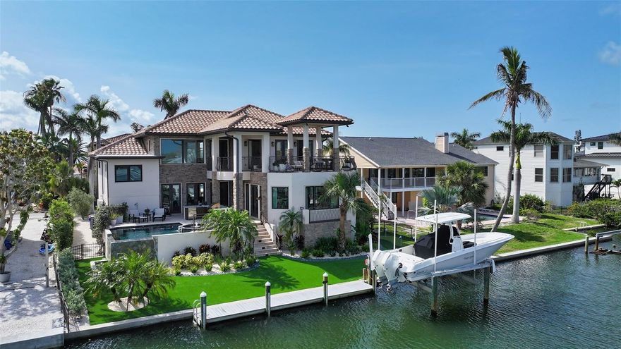 Refined coastal living is waiting for you at 795 Marbury Lane in Longboat Key. Perfectly positioned between the Gulf of Mexico and Sarasota's intercoastal waterway - this stunning waterfront estate combines high-end finishes and effortless access to open water. It's a boater's dream and an entertainer's paradise wrapped into one exceptional property! Generously sized with almost 3400 sf - this four bed (possibly 5) three bath home also offers a private study, separate gym and multiple living spaces on multiple levels. Designed with elevation and entertainment in mind - the home's transitional style is both warm and inviting - open and engaging. Built solidly with block construction and IMPACT WINDOWS, the home offers secure, storm-resilient living in one of Longboat Key’s most coveted locations. Step inside the meticulously landscaped courtyard and upon entry, witness stellar views to the pool and waterfront. You'll instantly notice the travertine floors, expansive French doors and volume ceilings. The chef's kitchen is the heart of the home - meeting the most discriminating chef's demands with custom cabinetry, SubZero refrigeration and freezer, Wolf induction range, Bosch dishwasher, Miele coffee station and oversized island with quartz counters. Entertain a crowd or have a quiet dinner with adjacent dining and living spaces - which flow effortlessly to the main patio. Bask in resort-worthy outdoor living with a saltwater infinity-edge pool and spa, outdoor grill and full summer kitchen - designed with a unique seating area for all your friends. Brand new artificial turf offers beautiful grounds without all the maintenance and a custom putting greeen keeps your golf swing in check. Did you say boating? Your private composite dock and 12,000 pound lift is waiting for early fishing trips and evening sunset cruises. It's just a few minutes to some of the best waters in Florida - where you're sure to spot dolphins and manatees on a regular basis! Grande and gorgeous, the owner's suite is a serene retreat to relax and unwind - with a fireplace, custom closets, extra room for a sitting area and French doors that open to a private deck complete with pergola, outdoor bar and fire pit. The bath is spa-worthy - with dual sinks, custom fixtures and storage, Toto toilet and oversized walk-in tiled shower. Three additional guest suites provide comfortable stays for your family and guests - with all the baths renovated in boutique-hotel standards. Throughout the home, enjoy remote-controlled automated shades, a whole-house water filtration system, tankless water heaters, designer lighting, expoxy garage floors, separate air conditioned gym and smart home enhancements. Located moments from Longboat Key’s top-tier dining, shopping, and Gulf beaches, this home is a flawless blend of timeless elegance, modern luxury, and waterfront living.