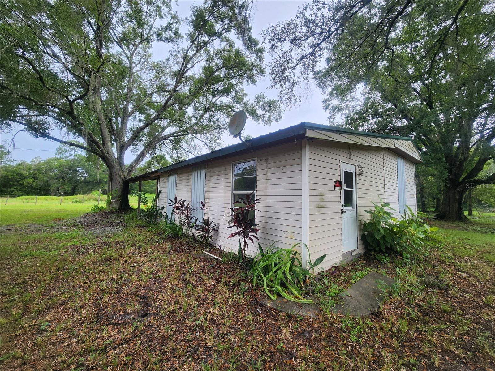 This home started as a mobile, and a large site built slab edition was built, almost doubling the size. The resulting home has 3 bedrooms and 2 living rooms all under a shiny new metal roof. Sitting back off a paved dead-end road, the house has been gutted and partially renovated with some rooms featuring new subfloor and drywall. There is plenty of work yet to be done (as seen in the photos). Outside you will find 2.22 dry acres divided into a large yard, and two flat, cleared, fenced pastures (fence needs repair in areas). One pasture features a metal livestock barn / shed that needs some work. Mature oaks scattered around give the property a feeling of a peaceful and picturesque lush green homestead. This neighborhood features ranches and farms. It feels like a world away, but all the modern conveniences of town are just a short drive away. Come finish the work that has been started, and you will be proud to call this one home.