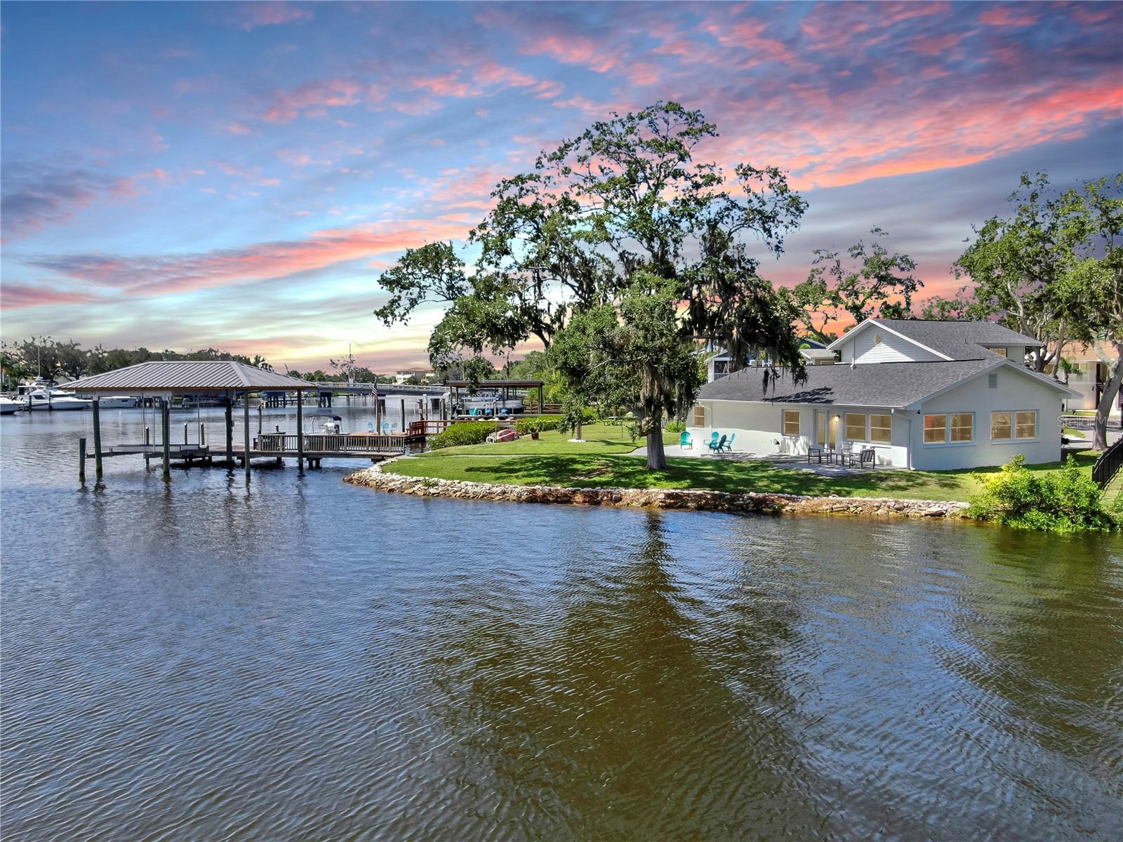 Welcome to coastal living at its finest! Located on a quiet cul-de-sac across from the Tarpon Yacht Club, this fully renovated 3-bedroom, 3-bath waterfront home offers 130 feet of deep water frontage with no tide restrictions on Tarpon Bayou with direct access to the Anclote River and Gulf, perfect for boating enthusiasts. The deep water canal stays navigable, even at low tide, a rare find! The covered dock with electric, 20,000 lb boat lift, and seawall with riprap make this a true boater’s paradise. Step inside to discover modern elegance and thoughtful upgrades throughout. Enjoy new wood and tile flooring, recessed lighting, impact windows, and custom storage solutions including a built-in wine rack, dining room cabinetry and custom closet organizers. The kitchen shines with new LG appliances, new cabinetry, high-end fixtures, and a craft refrigerator with craft ice. The spacious primary suite features his and her walk-in closets, a dual vanity bath, and luxe Delta fixtures. All three bathrooms have been renovated to include timeless, modern finishes. Upstairs, separate mini-split A/C systems provide personalized comfort. Recent updates include a new roof, HVAC and ductwork, tankless water heater, and upgraded electrical (all 2025). Enjoy a spacious interior utility room with a stainless steel sink, ideal for prepping boating or fishing gear, plus an exterior storage room for rods, tackle, and tools. Outside, unwind on the paver patio overlooking the water, surrounded by lush, freshly landscaped grounds and a gated circular driveway for added privacy. Located minutes from charming downtown Tarpon Springs, the historic Sponge Docks, Spring Bayou, Craig Park and Fred Howard Park, this home offers both privacy and proximity to shopping, dining, and the Gulf. Schedule your showing today!