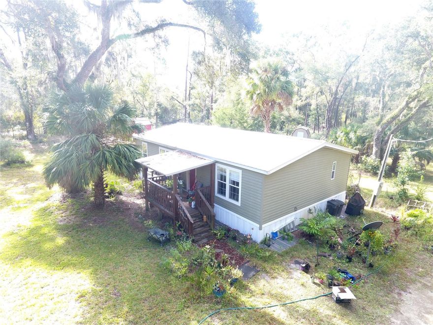 CHIEFLAND, FL ` 2014 PRACTICALLY NEW 3 bed/2 bath doublewide mobile home on 2.5 acres ~ Metal roof and A/C heat pump are only one year old! No hallways so no wasted space, just wide open floor plan, perfect for entertaining or stretching out and relaxing. Island kitchen with electric and breakfast bar, real wood cabinets, track lighting and kitchen sink window overlooks the back yard to watch the deer who frequent here. The stove is 4-burner gas with a griddle in the middle, but if you don't like cooking with gas, the electric plug is still available behind the stove. Eat-in dining area off the kitchen has chair railings and lighted chandelier. Primary bedroom is very spacious as well as primary bathroom which has a walk-in closet, garden tub, walk-in shower, and plenty of vanity counterspace. Lots of windows with blinds that are dual-pane for energy efficiency and so important for that all natural light to flow in. The walls are taped and textured, crown molding adorns the ceilings and floors. Outside there are several outbuildings which consist of a storage shed/workshop, screened room, a greenhouse, and a cute little cottage that has been finished out with flooring, walls, a loft, and a window a/c for your extra guests or make it an office if you choose. Very desirable corner lot, has two entry gates on each road providing easy access to your property for your vehicles, boats, 4-wheelers, etc. Approximately half of the property is cleared around the house with a wooded buffer along the rear perimeter for privacy and seclusion. Large beautiful grassed and landscaped front yard has fruit trees too. Welcoming covered front porch entry. Not in a subdivision, no deed restrictions, just quiet country living! Many local boat ramps, numerous pristine freshwater springs, but only 20 minutes to Super Walmart if you need to shop and 25 minutes to the island of Cedar Key and the Gulf of America. Low property taxes, and this home should qualify for all types of financing, including no money down USDA. Call for an appointment to see it today!