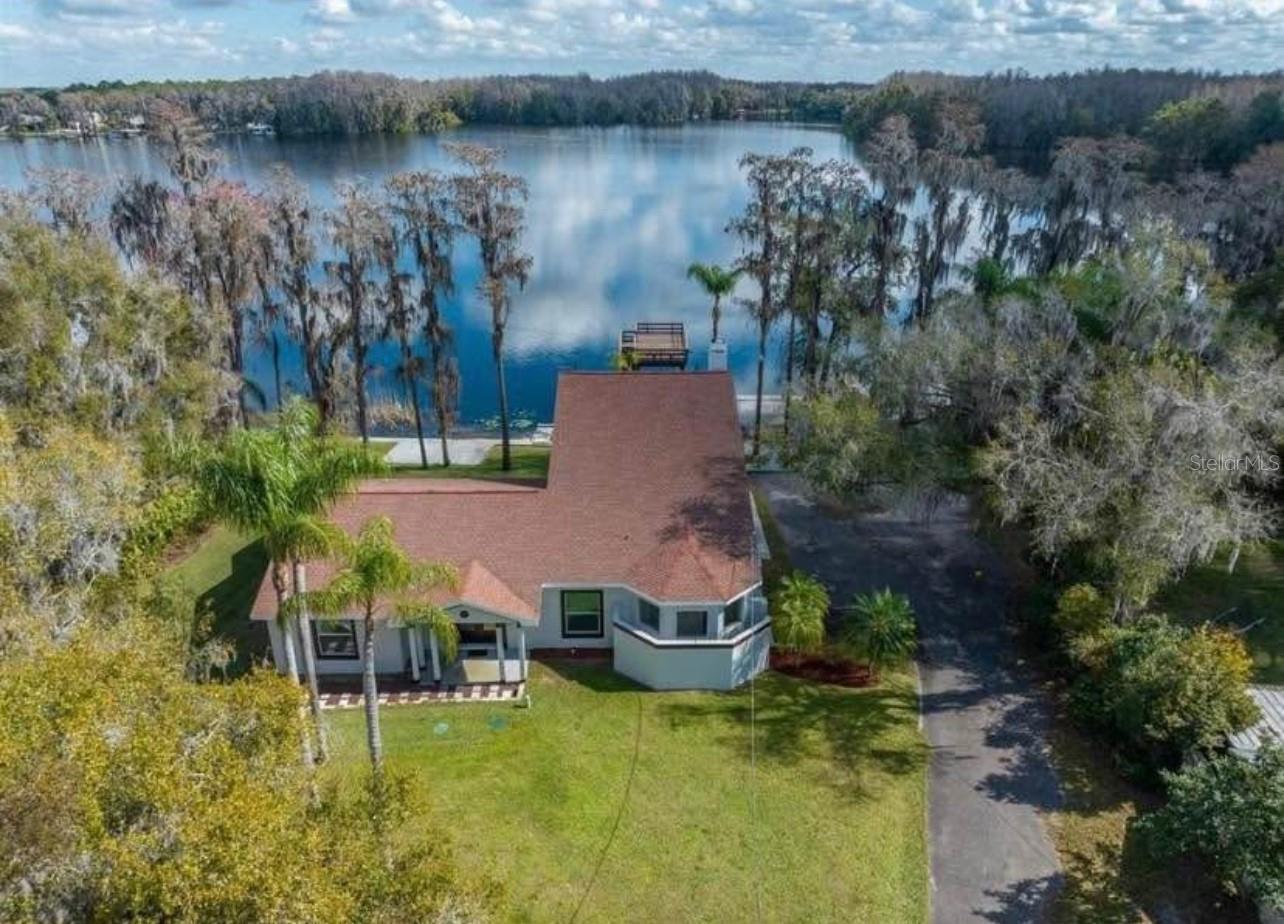 Lakefront Gated Estate on 3.2 Acres with Two Homes, Private Dock, and Jet Ski Lift
Experience lakefront living at its finest with this captivating gated estate on Lake Padgett, nestled on 3.2 acres along the deepest part of the lake. This unique property features two separate homes, a detached garage, private boat ramp, and a two-story dock with a sundeck and jet ski lift, offering privacy, space, and exceptional amenities.
The primary home welcomes you with a charming veranda adorned with tongue-and-groove ceilings, leading into a spacious family room filled with natural light and sweeping panoramic lake views. The kitchen is a chef’s delight, featuring granite countertops, stainless steel appliances, a breakfast bar, 42-inch crowned cabinetry, updated hardware, recessed lighting, and a gooseneck faucet. It's ideal for both entertaining and everyday living.
The primary bedroom is a true retreat, complete with walk-in closets, tile floors, and a cozy sitting area with a wood-burning fireplace and quad sliders that open to a covered lanai with wood-beam ceilings overlooking the lake. The en suite bathroom offers double vanities, granite countertops, a garden tub, and a walk-through shower with dual showerheads and tile accents.
Upstairs, a spacious third bedroom or bonus room features vaulted ceilings, new carpeting, and access to a full-length rear balcony with wood teak ceilings and incredible lake views. Additional highlights include a first-floor guest bedroom or office with custom paint, a formal dining room with French doors, new HVAC, new exterior paint, and an updated irrigation system.
The guest home, included in the total heated square footage, is a 1-bedroom, 1-bathroom mobile home featuring wood flooring, a spacious kitchen with a transom window, a large walk-in closet, and a full bath. It’s perfect for guests, multigenerational living, or rental potential.
Outdoor features include a private gated entrance, multiple storage sheds, a well house with water softener, and beautifully landscaped grounds leading to your own private waterfront escape.
Whether you're boating at sunset, relaxing on the sundeck, or enjoying time with family and friends, this is a rare opportunity to own a peaceful and private estate on Lake Padgett.