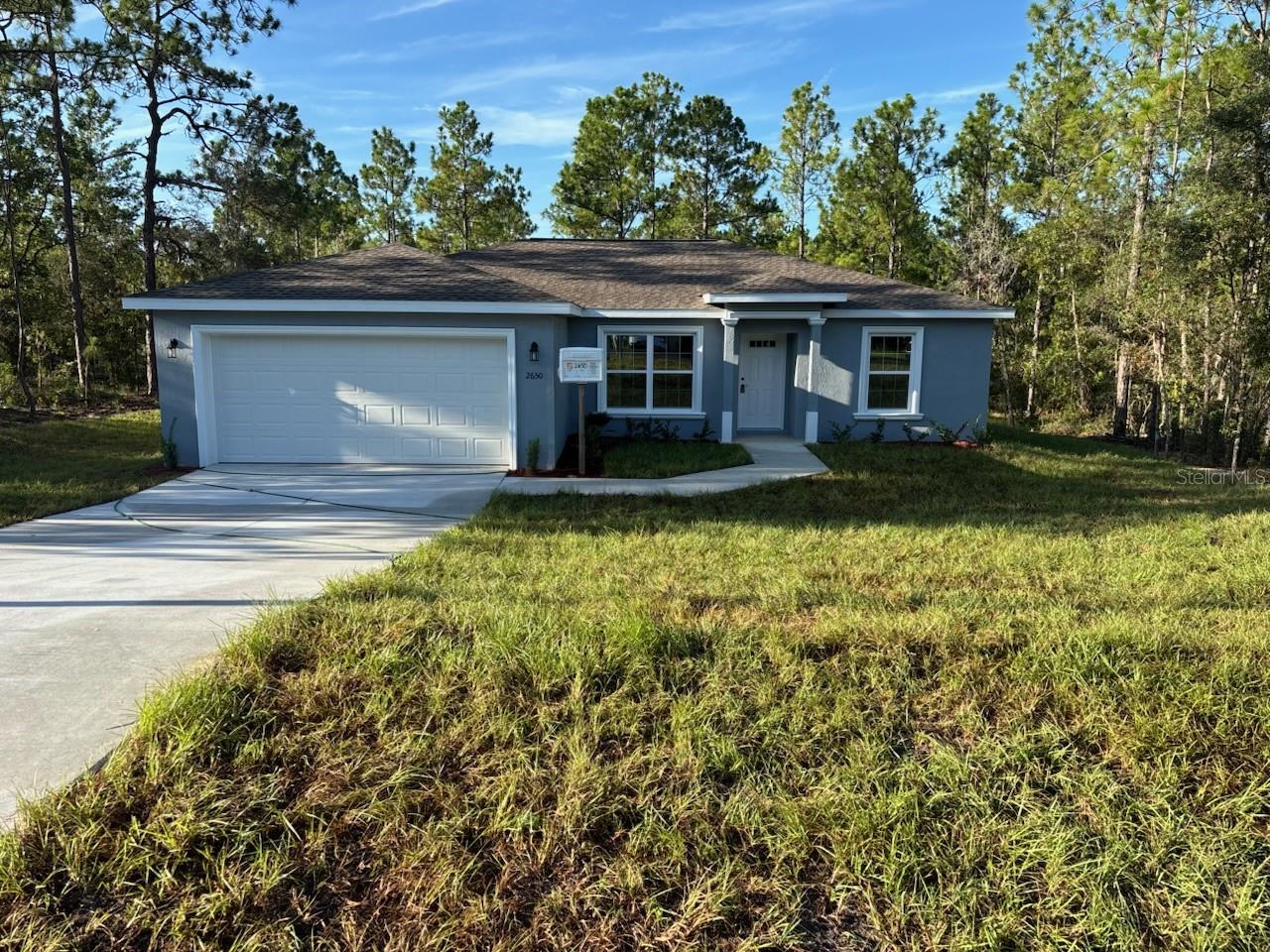 NEW CONSTRUCTION. MOVE-IN READY! This beautifully designed Key West model in Dunnellon offers 3 bedrooms, 2 bathrooms, and 1,405 square feet of comfortable living space. Sitting on a secluded lot at the end of a quiet street with woods behind, this home offers peace and privacy with very few nearby neighbors. Inside, you’ll find the builder’s largest master suite, featuring a spacious layout and a modern glass-enclosed shower with upgraded marble-look tile. The living room has a vaulted ceiling that adds to the open feel, and the kitchen is outfitted with stainless steel appliances, granite countertops, a subway tile backsplash, and custom white shaker cabinets with soft-close drawers. A kitchen pantry adds extra storage, and the luxury vinyl plank flooring runs throughout the entire home. The guest bathroom includes a tub and shower combo with matching upgraded tile. Enjoy energy-efficient double-pane windows, a 30-year architectural shingle roof, and concrete block construction built to last. The laundry room includes an upgraded cabinet package, and the attached 2-car garage comes with an opener and remotes. Relax outside on the covered patio, surrounded by natural beauty. Located in flood zone X, this home is high and dry and does not require flood insurance. Best of all, there are no HOA fees, giving you more freedom and flexibility.