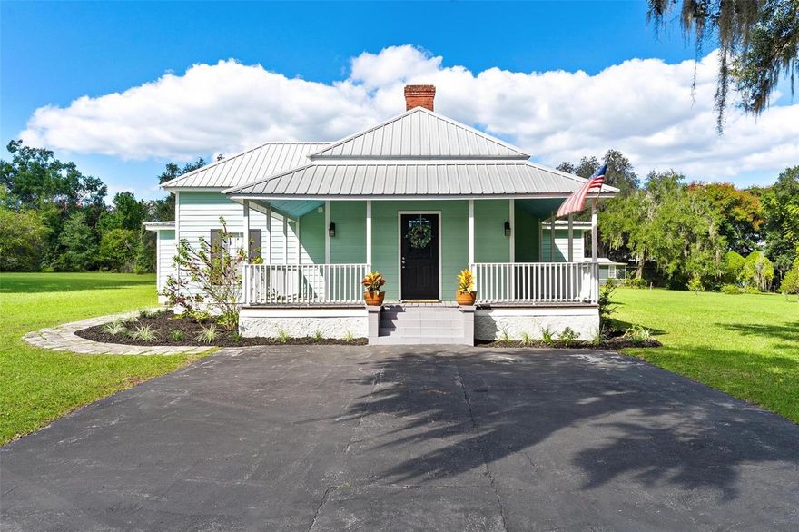 Full of charm and character, this beautifully restored historic home in Lady Lake offers the perfect blend of timeless style and modern updates. Nestled on 1.6 private acres, the property feels tucked away yet is just steps from local shops, services, and a short drive to The Villages. From the moment you arrive, the wrap-around porches and metal roof create great curb appeal. Inside, you’ll find plenty of charm with volume ceilings in both the living room and primary bedroom, accented with crown molding and decorative fireplace that adds warmth and elegance. The spacious, updated kitchen is truly the heart of the home, featuring bead board detailing, a large island with seating, an eating area, and a brand-new stove—perfect for gathering with family and friends. With 3 bedrooms, 2 bathrooms, and a convenient inside laundry room with outside access, the layout is designed for convenience! Beautiful laminate wood flooring runs through the bedrooms, while ceramic tile adds a polished finish to the rest of the home. Practical updates include a newer septic system and drain field, updated electrical service, and fresh paint inside and out. Two separate outbuildings, both with electricity, provide great storage. There is wonderful potential with the oversized parcel and a potential to divide the land and also potential to run an office or business with approval. With plenty of usable land, possibilities are endless! Come see how you can make your own history in this special Lady Lake treasure!