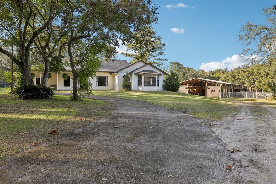 One or more photo(s) has been virtually staged. An exceptional private equestrian estate—where refined country luxury meets world-class performance facilities—just one hour from the renowned World Equestrian Center. Set on nearly five fenced acres, this rare offering is ideal for international buyers, professional trainers, or discerning equestrians seeking a turnkey Florida training base with privacy, infrastructure, and effortless livability. The custom 5-bedroom, 4-bath residence, including a private in-law suite. A spacious open floor plan showcases beautifully stained concrete floors throughout. The kitchen features stainless steel appliances, an eat-in dining area, expansive walk-in pantry, additional walk-in storage, and new LG stainless dishwasher, sink, and fixture installed in 2025. The kitchen flows seamlessly into the great room, anchored by a gas fireplace ideal for entertaining or everyday living. An expansive recreation/media room offers built-in bench storage, extensive electrical access, and a private exterior entrance leading directly to the resort-style pool—ideal for entertaining, staff use, or multi-generational living. The primary suite is a serene retreat with a spa-inspired bath, soaking tub, walk-in shower, and spacious walk-in closet. A thoughtfully designed mud and utility room with separate exterior entrance allows seamless transition from barn to home. The interior in-law suite offers full independence with a private entrance, kitchenette, living area, bedroom, and handicap-accessible bath. Equestrian facilities rival professional training centers. The 3,500-sq-ft main barn features eight stalls with electric and fenced runouts, with infrastructure in place to expand to ten. Each stall includes gossip rail doors, automatic waterers, and ceiling fans. A pavered center aisle is enhanced by oversized fans and double wash racks with hot and cold water. The lockable, climate-controlled tack room includes laminate flooring, eight bay tack closets, kitchenette, bathroom, washer/dryer hookup, and a see-through window overlooking the barn aisleway. The property offers five fully electric paddocks, including one with a two-stall, plus wash rack additional barn. The 100' x 200' arena is laser-leveled with premium fiber mesh footing and a custom viewing area, highly regarded by professional trainers. Supporting infrastructure includes a 1,200-sq-ft workshop with double carport, a 14x30 camper carport on a 30x30 concrete pad with 30- and 50-amp service, plus additional 30-amp service at the front of the property—all with water access. There is ample room for trailers, equipment, and guest parking, and the home benefits from a fully irrigated landscape. Outdoor living is resort-inspired with a pool, expansive decking, covered pergola, and tranquil stream, waterfall, and fish pond framed by rock-wall landscaping. A side yard fire pit and tree swing complete this private retreat. Gated and fully enclosed with no-climb fencing, this refined equestrian estate presents a rare opportunity to own a professionally equipped Florida horse property—just one hour from the World Equestrian Center, Clarcona Horseman's Park, and Rocking Horse show grounds, just to name a few. Multiple riding trails where you could ride and/or camp for days and never cover the same trail twice. Minutes to major roads and shopping—perfect for international competition, professional training facility, seasonal residency, or long-term investment.