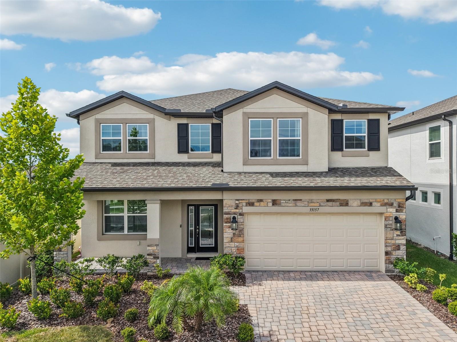 Under contract-accepting backup offers. One or more photo(s) has been virtually staged. $140,000 IN BUILDER UPGRADES to this incredible 5-bedroom, 4-bathroom luxury home in the highly sought-after, gated Watergrass community of Whispering Oaks Preserve. From the moment you arrive, the charming pavered driveway and walkway signal that you've found something special. Tasteful appointments & luxurious upgrades at every turn!
Inside, elegant tile flooring flows throughout the OPEN-CONCEPT living spaces. The flexible floor plan is brilliantly designed with TWO PRIMARY SUITES—ONE CONVENIENTLY LOCATED ON THE MAIN LEVEL AND A SECOND UPSTAIRS. The downstairs primary bath is a private retreat, featuring dual sinks and a sleek, walk-in shower.
Host gatherings with grace in the FORMAL DINING ROOM, SERVICED BY A CHIC BUTLER'S PANTRY. The heart of this home is the showstopper gourmet kitchen, where a dramatic QUARTZ WATERFALL ISLAND takes center stage. Custom details abound, from the UPGRADED BACKSPLASH AND INDUCTION COOKTOP TO THE DOUBLE OVENS AND LIGHT GRAY, 42” SOFT-CLOSE CABINETRY WITH CROWN MOLDING. The adjacent family room invites relaxation with its COZY ELECTRIC FIREPLACE, FRAMED BY STYLISH SHIPLAP.
Ascend the MODERN STAIRCASE WITH CABLE SPINDLES to a VAST LOFT/BONUS AREA, an entertainer's dream complete with A BUILT-IN WET BAR, CABINETRY, AND AN ELEGANT TRAY CEILING. The magnificent upstairs primary suite also boasts a tray ceiling and a spa-like ensuite bath, showcasing a LARGE WALK-IN SHOWER WITH HERRINGBONE TILE, A GARDEN TUB FOR SOAKING, QUARTZ COUNTERTOPS AND DUAL SINKS.
THIS HOME IS FILLED WITH PREMIUM FEATURES, including a LAUNDRY ROOM WITH BUILT-IN CABINETRY (WASHER AND DRYER INCLUDED) and an EPOXIED GARAGE FLOOR. Step outside to the EXTENDED COVERED LANAI, where the possibilities are endless. This outdoor space is the perfect canvas for your dream oasis, as it comes PRE-PLUMBED FOR A GAS GRILL AND PRE-WIRED FOR A FUTURE POOL, making your vision for outdoor living an easy reality. All this, with the added convenience of BEING LOCATED NEXT TO THE COMMUNITY PLAYGROUND.