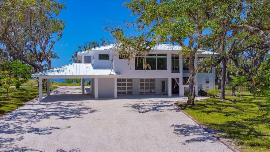 Sitting on over 7 acres, This STUNNING upscale, resort style home is one that will fit any lifestyle! Whether you are looking for your own personal getaway or somewhere to make memories that last a lifetime; this is the place to be! The long, circular driveway will lead you directly through your own personal porte cochere, which is sure to impress. The downstairs quarters are perfect for a grand entertainment experience which includes a HUGE, screen enclosed, patio area fit with a BBQ firebox with firebrick interior, a stainless steel, wood burning Argentine grill, and a built-in 4 rack smoker. There is an abundance of seating space with a center mounted TV to help serve as host for any type of event. Once you step onto the back patio, the view can be breathtaking! Overlooking the Manatee River, you have your own private deck with multiple swings to sit back, relax, watch the sunset, along with views of manatees, dolphins, river otters, and other Florida wildlife! In addition to the deck, there is a private boat ramp on the north side of the lagoon AND a separate boat dock with a lift that provides an easy ride along the river and into the Gulf of Mexico! As for the upstairs quarters back at the house; whether you take the elevator or the stairs, you will find ultimate luxury and comfort. Starting in the kitchen, you’ll find solid wood cabinetry that houses ample storage space. The kitchen includes a SubZero Refrigerator and a 102-bottle wine rack, along with a double gas griddle with electric two door range, and a built-in micro drawer with tilt control. With the open floor plan, you will never miss out on any action in the living area. When you’re ready to watch TV, with the click of a button, the TV will glide down from its hidden compartment at your leisure. With such amenities and the 180-degree riverfront views, it's doubtful that you would want to take the short 10-minute ride to the city when you have your own oasis to call home. Each of the three bedrooms feature near floor to ceiling windows to enjoy the amazing, picture-perfect views along with their own private en suite bathroom. Almost every room has direct access to the upstairs, wrap-around porch, that can lead you straight to your outdoor plans. Conveniently, you will find a backup generator with 500G propane tank, and Sonos sound system with speakers in every living space, including the deck, screened room, carport and garage as well as both docks to enhance the overall, spectacular, experience. This house is a rare find. Every little detail was custom built to ensure sustainability, energy efficiency and to upkeep the luxurious, yet comfortable lifestyle.  Make sure to schedule an appointment today to see this beautiful home!