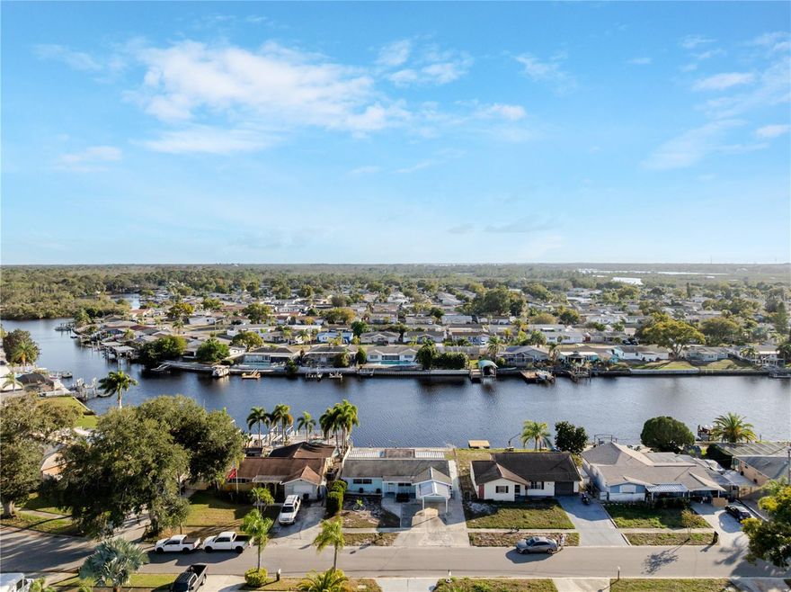 Welcome to an exceptional opportunity to enjoy Florida waterfront living at its finest in this beautifully updated 3-bedroom, 2-bath residence, where comfort, style, and peace of mind come together seamlessly. This home has never flooded under current ownership and features a brand-new roof scheduled for installation on 1/19, along with thoughtfully completed interior updates within the last six years offering a truly move-in-ready experience. Fresh exterior paint enhances the home’s charming curb appeal, while the fully fenced yard provides both privacy and flexibility.Large carport perfect for shaded parking and added convenience. Step outside to the inviting rear patio overlooking a wide and scenic canal, an ideal setting for entertaining guests, relaxing after a long day, or enjoying breathtaking sunset views that create a serene waterfront ambiance. Boating enthusiasts will appreciate the expansive, navigable canal with direct waterfront access, complemented by a substantial seawall and ample space to accommodate a variety of watercraft. With no HOA and no CDD, this property offers the freedom to embrace the waterfront lifestyle without restriction. Ideally situated in the desirable Holiday area, this home is conveniently located near parks, shopping, dining, and provides easy access to the Gulf of Mexico making it a perfect blend of coastal luxury and everyday convenience. Schedule your showing for this one of a kind property before it’s too late!