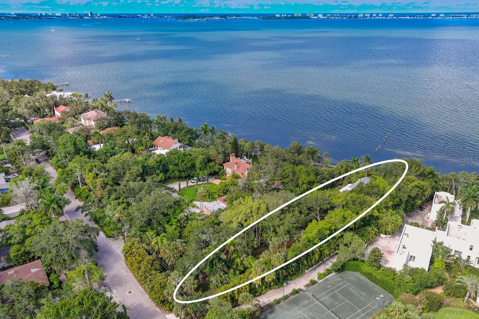 Exotic and extremely private bay front property on the market for the first time in 40 years. In fact, this is only the third time it’s been available in 100 years. Travel back in time to find ancient oaks and large palms, Banyans, and cedars. It’s an idyllic paradise reminding us of why people have come to these shores for millennia. Although this is direct waterfront, most of the land is not in the flood zone creating many possibilities for new structures on or near grade. What is most unique is the 444-foot lot depth. This is almost 4 times that of other bayfront parcels being redeveloped in the area. This extreme distance provides complete privacy from Bay Shore Road and with each adjacent property a multi-acre estate, the feeling of spaciousness and seclusion is complete. Leave the world behind on the long, winding shell drive through tree canopy and lush vegetation. At “the end of the road” is the original homesite on a small bluff directly on and overlooking Sarasota Bay. Your views are of Longboat and Lido Key and out New Pass to the Gulf of Mexico. Looking south you see our bustling little city of Sarasota and the John Ringling Bridge. Enjoy sea breezes in the afternoon and sunsets all year round. A parcel like this is an architects dream providing the size necessary to create what anyone might want, elevation allowing cascading terraces down to the waterfront and multiple, potential “footprints” for accessory dwellings, accessory structures and more. Bay Shore Road has become an eclectic location for the grandest homes in Sarasota. This has led to sales over 10 million dollars and have exceeded 15 million. But you could not put a price on the most spectacular neighbor, Ca’ d Zan. John Ringling’s gilded Venetian palace anchors the neighborhood to the north and downtown Sarasota is just 2 miles south. Other nearby cultural & educational institutions include the Ringling Museum of Art, the Asolo Theater of Performing Arts, the Sarasota Ballet, the Ringling College of Art & Design and our newest amenity, The Bay Park Conservancy redeveloping 53 acres of City waterfront into a world class public park.