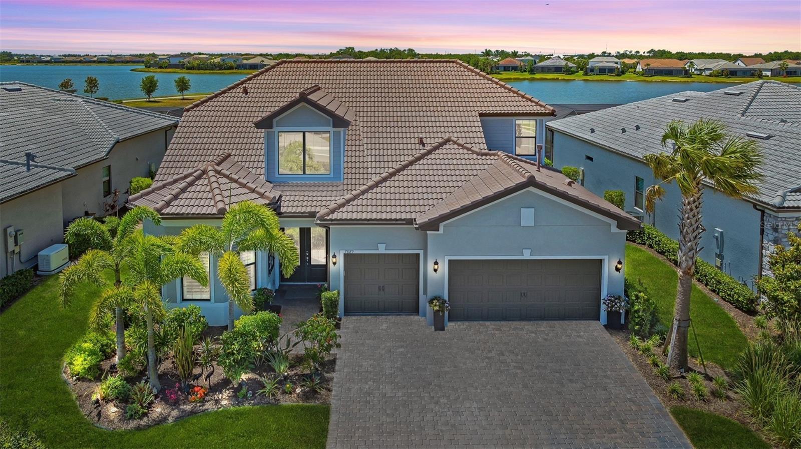 Positioned on a premium south-facing lakefront homesite with tranquil water views, this exceptional residence in Lakewood Ranch Waterside combines luxury, comfort, and versatility in one of the area’s most desirable settings. The main level showcases a thoughtfully designed great room floor plan with soaring volume ceilings, crown molding, and custom coffered detailing, creating an open and inviting atmosphere. The kitchen serves as the heart of the home, featuring a large leathered quartz island with seating, a gas cooktop, stainless steel appliances, and an expansive walk-in pantry. Step outside to an impressive outdoor living space, where a saltwater pool and spa are perfectly screened with clear-view panels, maximizing the expansive lake views. The covered lanai offers generous space for both dining and lounging, creating an ideal environment for relaxation and entertaining. Inside, the primary suite offers a peaceful retreat with a walk-in shower, private water closet, and an oversized dressing room with custom organization. Two additional bedrooms and bathrooms on the main floor provide comfortable accommodations for family or guests, while the second level offers a spacious bonus room, fourth bedroom, and full bath—perfect for visitors, working from home, or recreation. Shoreview residents enjoy resort-style amenities including a clubhouse with pool, spa, indoor and outdoor bar, lakeside dock with kayak launch, tennis, pickleball, bocce, fitness center, fire pit, event lawn, and dog parks. Easy access to Water Taxi to Waterside Place where you can enjoy vibrant shops, restaurants, and events. This residence is also just minutes to Lakewood Ranch Main Street, University Town Center, I-75, highly-ranked schools, premier healthcare facilities, and the pristine white-sand beaches of the Gulf Coast.