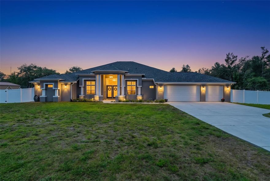 Built in 2024, this custom 5-bedroom, 3-bath residence offers over 3,500 sq ft of refined living on a fully fenced nearly one-acre homesite in Weeki Wachee, FL, where thoughtful design and open-concept living come together with intention. A grand entry welcomes you through glass panel double doors, opening into a light-filled interior enhanced by plantation shutters throughout every window, delivering a polished finish with a timeless feel. At the heart of the home, the kitchen is both striking and functional, centered around a 10-foot island offering additional seating and workspace. Extensive cabinetry, an oversized walk-in pantry, and a bright breakfast nook create a natural gathering point that connects daily living with effortless entertaining. Flowing beyond, the expansive living room makes an immediate impression with its openness and detail. A custom accent wall with built-in storage is designed to comfortably accommodate an 80-inch TV, paired with a sleek electric fireplace and warm wood beam shelving that adds texture and depth. The layout feels open yet defined, ideal for both entertaining and relaxed evenings at home. The primary suite offers a private retreat with generous proportions and a calming atmosphere. The bathroom becomes the focal point, featuring a deep soaking tub, oversized walk-in shower with three rain showerheads, and spa-inspired finishes that elevate everyday routines. Four additional rooms reflect the scale of the home and are thoughtfully placed to support privacy and flexibility for guests, work, or additional living space while maintaining comfort and continuity throughout. Glass pocket doors extend the living area outdoors, opening to an expanded lanai designed for year-round enjoyment. Two ceiling fans provide comfort during Florida’s warmer months, making it an ideal setting for relaxing or entertaining. The fully enclosed backyard with white vinyl fencing offers open outdoor living with room for a future pool, outdoor kitchen, or custom retreat. A three car garage adds exceptional convenience, offering extra room for multiple vehicles, storage, recreational gear, or even a workshop space, helping keep daily living organized while maximizing interior functionality. A home that prioritizes livability, comfort, and modern scale, designed to feel elevated and welcoming from the moment you arrive.
