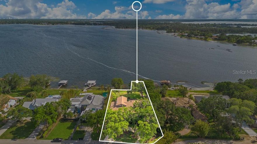 Experience true lakefront living on the famed Butler Chain of Lakes. This exceptional custom home offers 137 feet of pristine shoreline and sits on nearly one acre of high, dry land with sweeping panoramic water views and nightly Disney fireworks. Arrive via a circular paved drive framed by mature oaks and step onto the covered porch through an impressive 8 inch solid cedar entry door with artisan leaded glass. Inside, the great room makes an immediate statement with soaring 23’ cathedral ceilings and a striking Tennessee river rock fireplace. Entertain in the showstopping formal dining room, where oversized picture windows perfectly frame the lake. Designed for everyday comfort, the majority of the living space including all bedrooms is located on the main level. The chef’s kitchen is fully equipped with solid wood cabinetry, granite countertops, Sub-Zero refrigerator, Thermador gas cooktop with exhaust, Bosch double ovens, wet bar, walk-in pantry, and a sunlit breakfast area with spectacular water views. The spacious primary suite is a private retreat with its own screened lanai and a spa-inspired bath featuring a shower, jetted tub, dual vanities, and three walk-in closets. Generous secondary bedrooms offer ample closet space and well appointed baths, including a steam shower. Outdoors is where this home truly shines. Enjoy mature landscaping and colorful gardens, plus a motorized screened lanai with a chef-worthy summer kitchen pizza oven, prep area, grill, refrigerator, and TV alongside the pool, heated spa, and gas firepit. The desirable southern exposure delivers refreshing lake breezes and comfortable outdoor living without harsh afternoon sun. The custom floor plan maximizes lake views throughout, and the partially enclosed dock is a rare find grandfathered in, with a boat lift and side jet-ski lift. Additional highlights include newer doors and windows and a tile roof. The Lakes neighborhood also offers a community boat ramp and tennis courts. Enjoy Windermere living on the Butler Chain without the traffic, just minutes from major roads, top schools, shopping, and dining. This rare, well-built lakefront home is ready to welcome you. Be sure to explore the virtual tours.