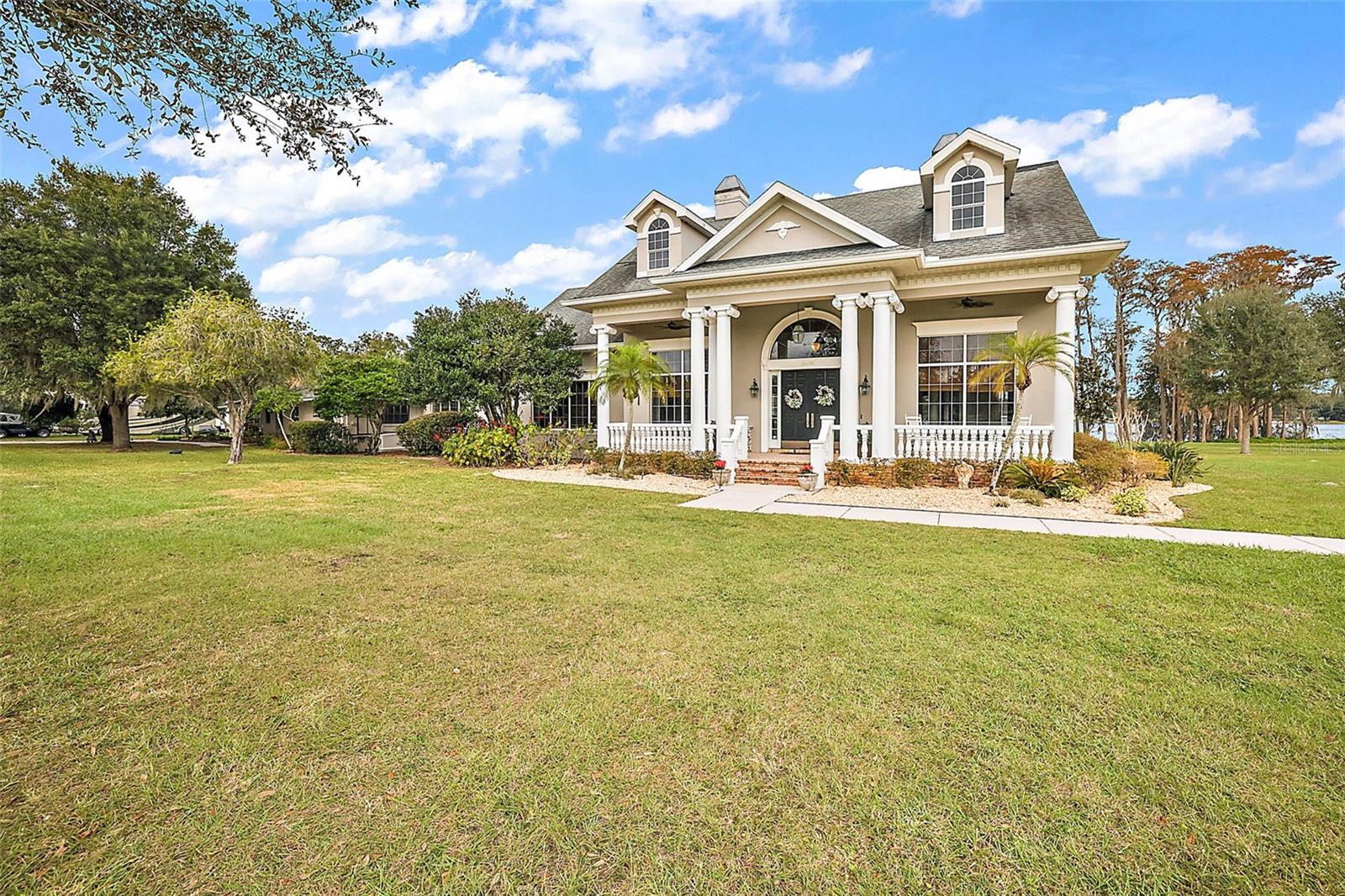 LAKE FRONT • 10+ACRES • BOAT DOCK • BREATHTAKING VIEWS • BEAUTIFUL 4 Bed 5 Bath Estate! Wow Factor All Around! From the very first time you drive onto this property you experience a unique sensation of awe, freedom, empowerment, and pride all swirled together as you survey the grand oaks with beautiful wind-swaying Spanish moss, the lush green pastures and the crystal clear spring-fed Clear Lake beckoning you to indulge in fishing, skiing, kayaking, canoeing, and all the joy that it brings. The private gated entrance leads you down the crape myrtle and golden rain tree lined path to the stately private residence. The house was built in 1976 and an impressive custom addition in 2005. **NEW ROOF 4/2024** The house boasts of 4493 square feet with 4 bedrooms, 3 full baths and 2 half baths; 16x18 great room with hardwood floors and 13’ ceilings, an elegant gas fireplace, and built-in bookcases; 14x33 owner’s suite with hardwood floors, custom closets, and a spacious en suite with large soak tub, separate shower and double vanity sinks; a second 16x17 owner’s suite; a gorgeous custom kitchen with granite counters, stainless steel appliances, double oven, breakfast bar, and an open floor plan to include 17x22 dining area and cozy wood burning river rock fireplace family room. Unwind and enjoy peaceful breezy days on the 10x39 screened lanai watching Florida wildlife and sunsets overlooking the spring fed lake. Entertain friends and family around the master-griller bbq-pit by the private lakeside white-sand beach. Grab your fishing gear, head down to the boat dock and spend your morning on 50 acre Clear Lake. If homesteading is your pleasure, spread out on the vast 10+acres with your cows, chickens, goats and gardening. Property has a chicken coop with enormous covered run and bunny coops; 24x10 garden shed/culinary well house; a large fenced garden and fruit trees. The possibilities are endless with this amazing property! 2022 30x50 insulated, 220 power, metal shop building with two 12x50 lean-tos with sides; Large cypress wood barn with 2 horse stalls, 50 amp service, water, and fenced paddock, recently raised rafters in barn to accommodate a Tiffin Allegro Bus RV; private boat dock & ramp; 2020 6 person hot tub; fully fenced property; 2020 Generac whole house generator and hook up; 2 wells; 2 septics; 3 a/c’s; 8x8 irrigation well house;14x12 bbq shed with brick floor and cedar plank serving bar; 16x28 lake shed with large service panel; 2022 16x40 partially finished cabin with potential for short term rental or guests; 16x45 RV cover; 1,000 gal propane tank recently filled. Located in a quiet rural area yet convenient to (2 mi) shopping, restaurants, (3 mi)schools, unique shops, dining and events of (8mi)Mt. Dora, and quick access to the 429 connector. Bedroom Closet Type: Walk-in Closet (Primary Bedroom).