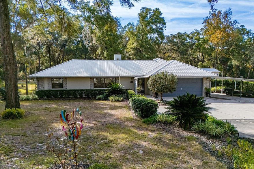 Beautiful custom 3BR/2BA concrete block stucco ranch home set on 10.3 acres, offering privacy, space, and comfortable living. Inside, a striking rock fireplace anchors the main living area, creating a warm and inviting atmosphere. The Florida room is designed for entertaining with a large wet bar and a spacious layout ideal for gatherings. The kitchen features a large walk-in pantry, providing ample storage and convenience for family and entertaining needs.
Outside, the home features a 2-car attached garage, a 2-car carport, and a 3-car detached garage with workshop, along with a large parking apron and paved driveway providing ample space for vehicles, RVs, and guests. The expansive rear patio includes a gas grill supplied by a buried propane line that runs directly to the grill area with no portable propane tanks needed and a custom-built pagoda-style pergola, creating an ideal outdoor entertaining space.
The property also includes a whole-house generator fueled by the same buried propane tank, automatically powering the home including HVAC and appliances during outages and seamlessly restoring service once power returns. There is a dedicated RV hookup for added convenience. In the backyard, a separate plumbing and septic system independent from the main house is ideal for an RV or future use.
Approximately five acres surrounding the home are beautifully landscaped, creating a park-like setting with perennial gardens, secret garden walkways, and a remarkable variety of established trees and plantings, including live oak, magnolia, satsuma orange trees, cabbage palms, sago palms, catalpa, pawpaws, bamboo, ligustrum, slim bottle brush, Simpson stopper, Ocala anise bushes, flatwoods plum, bougainvillea, and chaste trees. The remaining acreage is left relatively untouched and wooded, providing natural privacy, abundant wildlife habitat, and room for future use or enjoyment. Longleaf pine and hickory seedlings are planted throughout the open acreage, and a fenced backyard, garden oasis, and abundant wildlife including deer and turkeys complete this exceptional property.
Conveniently located just five minutes from town and close to schools, shopping, a golf course, Suwannee River State Park with natural springs, the Gulf of Mexico, Cedar Key, and with easy access to Gainesville. Don’t miss the opportunity to see this one-of-a-kind property! Schedule your private showing today!
