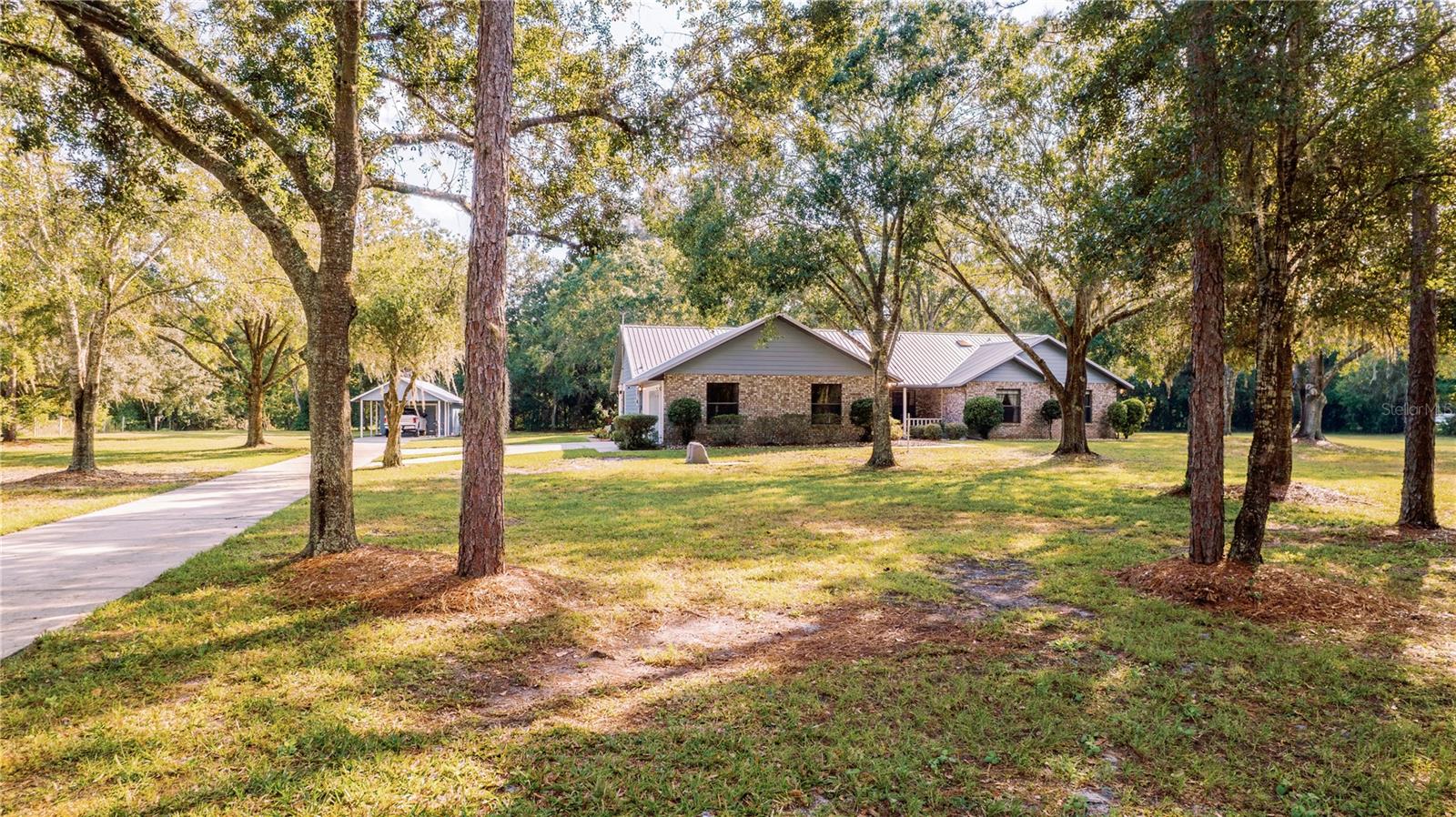 CUSTOM brick-accented home, situated on 2.4 acres......with a DETACHED WORKSHOP & CARPORT!!!  METAL ROOF IN 2004, NEW A/C IN 2021, many double-paned windows, NEW WATER HEATER IN 2025, and in mint condition!!  BEAUTIFUL FIREPLACE upon entering the front door......vaulted ceilings, skylights, wainscoting, SPACIOUS ROOMS, HUGE kitchen with an island and a built-in workstation. We have outlets in the island and the formal dining is also oversized. ALL APPLIANCES WILL STAY, EVEN THE WASHER & DRYER. The Owner's Suite is tucked down its own mini hall......boasts TWO closets (1 being a big walk-in), and a private bath with dual sinks, a stand-up shower, & a soaker tub. Beds 2 & 3 have NEW CARPET, a HALF BATH is convenient for guests, & our Laundry room is INSIDE! There are extra hall closets, newer blinds, marble sills, gutters, an active TERMITE BOND, & a PHENOMENAL FLORIDA ROOM. Comprised of many windows, a cedar ceiling, central a/c.........this room could be an amazing den, office, crafts or hobby space, & would make that superb additional gathering area for family & friends. The garage has a SIDE ENTRY, is larger than most, offers a utility sink, a bump-in nook for storage, & there is also a GENERATOR OUTLET IN PLACE.  STORM BOARDS WILL STAY WITH THE HOME FOR WINDOW/DOOR PROTECTION.  This garage & the DETACHED workshop both have door openers. Our WORKSHOP has a NEW ROOF AS OF THIS YEAR........there is shelving, lights/power, & benches. The property is GORGEOUS!!  Mature Oaks, Maples, & Pines add great shade and panoramic views. LOOKING TO SPLIT THE PARCEL & BUILD ANOTHER HOME??  That possibility may exist......there is approximately an acre on the west side of this property that could make another homestead or offer the space for a second home. Please ask your Realtor for more info and/or Osceola County agencies.  Location is IDEAL......the FL Turnpike is within 4+ miles, OIA is within 22+ miles, East Coast Beaches in 49+ miles, our famous attractions within 28+ miles, downtown St. Cloud shops/eateries & lakefront park in 6+ miles, & Lake Nona is within 18+ miles. NO HOA, NO CDD, NO WATER BILL.........ONE-OWNER & METICULOUSLY MAINTAINED. Not many on the market, make sure to book your private showing to see all we have to offer.