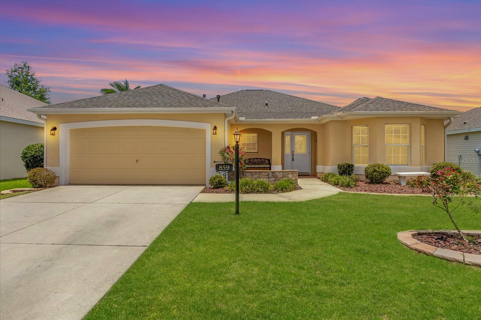 WALK TO LAKE SUMTER LANDING! Located in the highly sought-after Village of Virginia Trace, this beautifully maintained block and stucco home is truly steps away from all the shopping, dining, and nightly entertainment at Lake Sumter Landing Square—a rare find! Curb appeal shines with stacked stone landscaping beds, a charming front porch, and Florida-friendly landscaping. Inside, you'll find large ceramic tile laid on the diagonal throughout the entry, kitchen, living, and dining areas. The interior has been professionally painted, creating a clean and inviting feel throughout. The chef’s kitchen is sure to impress, boasting granite countertops, an abundance of workspace, and stainless steel appliances, including a side-by-side refrigerator, microwave, and dishwasher. Enjoy your morning coffee in the kitchen nook, where you can look out over the front of the home and catch up on the day’s activity. The spacious laundry room offers extra versatility with room for a small desk or additional pantry space. All three bedrooms feature wood composite flooring, and the primary suite includes dual closets and an en-suite bath with dual vanities and a walk-in shower. Unwind after a full day of Village fun in the enclosed, tiled lanai or step out onto the private brick patio, ideal for grilling and enjoying the privacy landscaping. A newer roof was installed in 2022 creating peace of mind for years to come. This is a rare opportunity to own a centrally located home just steps from The Villages’ most popular square—don’t miss out!