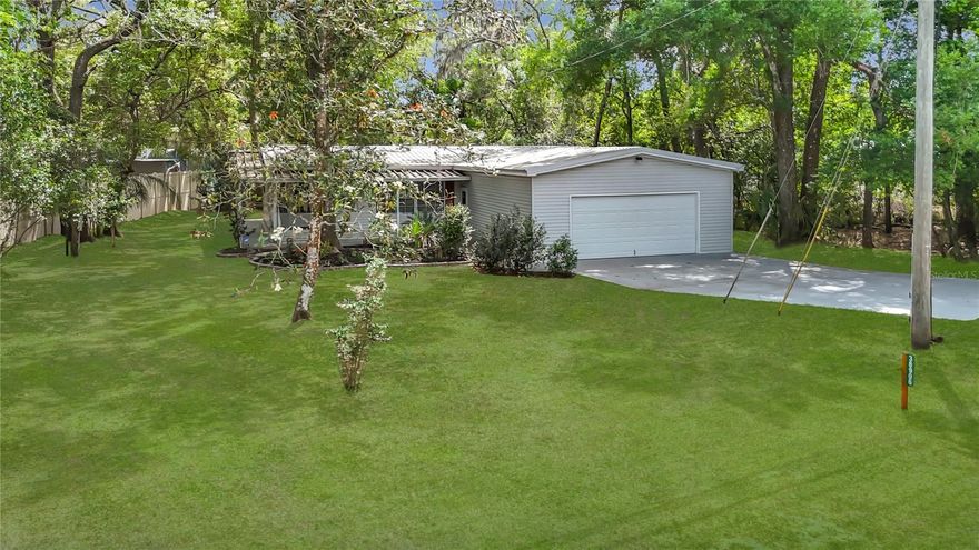 One or more photos have been virtually staged. Don’t miss this rare opportunity to own a charming 2-bedroom, 2-bath manufactured home nestled on over ? acre, offering plenty of space and privacy. This property features a 2-car garage on a slab, an extended concrete driveway, and a welcoming front porch perfect for enjoying your morning coffee. Step inside to a spacious living and dining room combo with laminate flooring, built-in cabinets, a new light/fan fixture, and sliding doors that open to the lanai. The eat-in kitchen boasts newer countertops and a stylish shiplap backsplash, ideal for preparing meals and entertaining guests. The master bedroom is generously sized with a walk-in closet and built-in cabinets for extra storage, while the master bath has a new toilet for added comfort. The second bedroom also offers ample space, and the second bath includes a new vanity. Out back, relax in the spacious vinyl lanai overlooking a beautiful backyard filled with mature trees, a garden path, and two lemon trees. Additional features include a slab perfect for grilling and another slab ready for a shed, making this home the perfect blend of comfort and functionality. Recent updates included metal roof 2015, AC 2018, and re-piped in 2024. Close to highway for quick access to the airport, Tampa, Clearwater and St. Pete Beaches (Ranked in the top 5 Beaches in the US), also close to shopping and restaurants. Come see this home before it's gone!