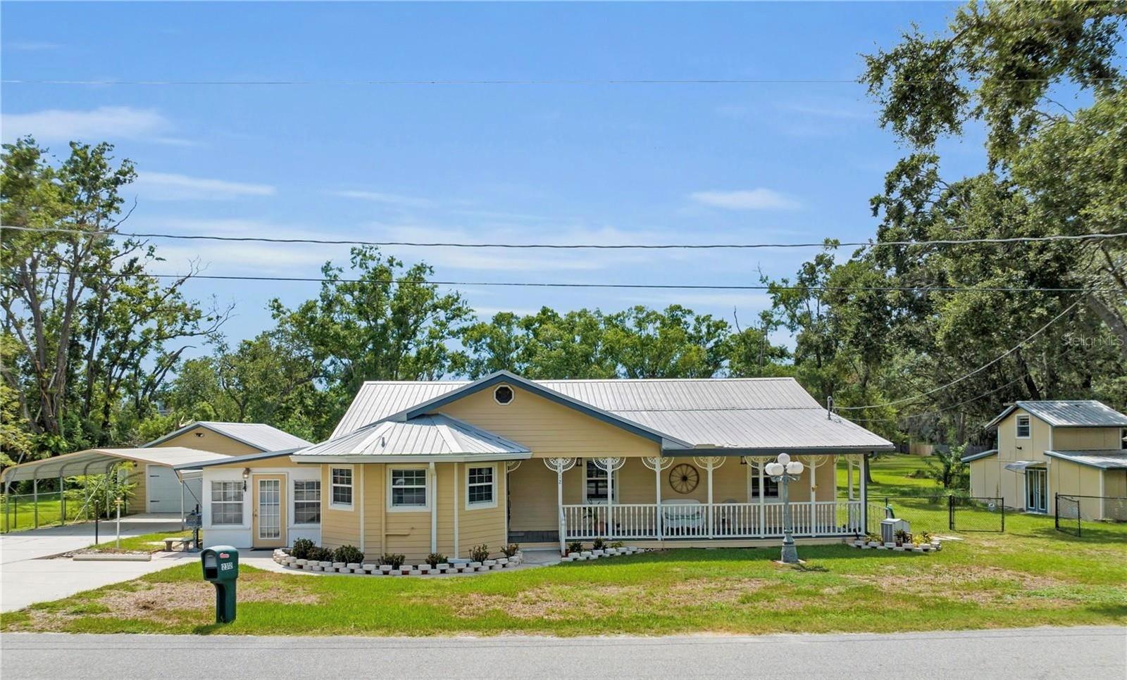 Welcome to a truly special property that is the definition of a one of a kind home! This property is in a prime location, just moments from shops, dining, and highway access, yet tucked away on nearly 3 private, picturesque acres with no HOA. This custom 3-bedroom, 2-bathroom home offers a unique blend of charm, space, and tranquility rarely found on the market. Enjoy exclusive access to a serene, nearly private lake shared with only a few neighboring homes. A private dock, boardwalk, and gazebo provide a peaceful outdoor setting perfect for relaxing or entertaining. The detached two-car garage/workshop adds both functionality and flexibility. A separate guest cottage/ADU offers additional living space, complete with a loft, kitchenette, and full bathroom, which is an ideal setup for visitors, extended family, or potential rental income. Inside the main residence, you'll find thoughtful craftsmanship and rich character throughout. Beautiful wood paneling adds warmth and texture to the home. The one of a kind kitchen features a massive central island, making it a true centerpiece for gathering and entertaining. Two light-filled sunrooms provide inviting spaces for morning coffee or afternoon relaxation. An expansive laundry and pantry area offers optimal storage and everyday function. The living room centers around a wood-burning fireplace with custom brickwork and exposed wood-beam ceilings, adding depth and charm to the space. Additional features include a durable metal roof, two-car carport, fresh professional landscaping, and a welcoming wraparound front porch that perfectly complements the home’s custom design. This is not just a house, it’s a lifestyle property filled with soul, uniqueness, and endless possibilities. You won’t find another home like this. Contact us today to schedule your private tour. This one won’t last.