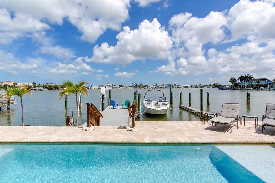 WELCOME TO YOUR WATERFRONT PARADISE IN NORTH REDINGTON BEACH WITH A LIFT AND WET SLIP!  This beautiful 3-bedroom, 2.5-bath coastal retreat offers the perfect blend of luxury, comfort, and effortless Florida living. Elevated construction, lush tropical landscaping, and striking curb appeal welcome you home as you step inside to soaring ceilings, abundant natural light, and breathtaking water views that immediately capture your attention.  Designed with both everyday living and entertaining in mind, the spacious open floor plan flows seamlessly from room to room. The inviting living spaces feature elegant finishes, custom details, and expansive windows that showcase the tranquil waterfront setting. The beautifully appointed kitchen offers generous cabinetry, ample counter space, breakfast bar seating, and opens directly into the main living and dining areas, creating the ideal atmosphere for gatherings with family and friends.  The newly renovated primary suite, conveniently located on the first floor, is a true private oasis. This luxurious retreat features spacious accommodations, beautiful flooring, and a stunning spa-inspired ensuite bathroom complete with modern finishes, dual vanities, soaking tub, and oversized walk-in shower. Upstairs, the additional guest bedrooms provide comfortable accommodations for family and visitors alike.  Step outside into your own tropical resort-style backyard where waterfront living truly comes to life. The expansive travertine pool deck surrounds the sparkling pool and jacuzzi, both equipped with a heater and chiller for year-round enjoyment. Relax in the sun, entertain under the stars, or simply take in the wide-open water views and coastal breezes. The dock offers quick access to the Intracoastal and Gulf waters, making this property ideal for boating enthusiasts.  Additional highlights include paid-off solar panels that greatly enhance the home’s energy efficiency, turf landscaping for low-maintenance living, a spacious laundry room, oversized 2-car garage, and multiple indoor and outdoor entertaining spaces. From the peaceful waterfront setting to the thoughtful upgrades throughout, this home embodies the very best of luxury coastal living in the heart of North Redington Beach.