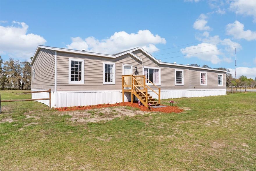 Welcome to your slice of country paradise—where wide open skies, fresh air, and the freedom to truly spread out come together on 2.6 beautiful acres. This spacious 4-bedroom, 2-bath manufactured home offers the perfect blend of comfort and rural charm, designed for those who crave room to roam and a lifestyle that embraces the outdoors.
Step inside to an open, airy layout featuring a generously sized living area that can handle it all—gatherings, game nights, family, friends, pets, and everything in between. The large kitchen is the heart of the home, complete with a serving bar and closet pantry, making it ideal for both everyday living and entertaining. A spacious laundry room adds even more convenience, with plenty of room for storage and functionality.  
Outside is where this property truly shines. Fully fenced and ready for your animals, this land is perfectly suited for horses, cows, and more. With a barn featuring four stalls and a tack room, a separate shed/bonus structure, and a dedicated dog run, every member of your crew has their place. Cool off on warm Florida days in the above-ground pool, then unwind and take in the peaceful surroundings.
Enjoy the best of country living without sacrificing convenience, ideally located just a short drive to Ocala and The Villages. Whether you're starting your own mini farm, expanding your space, or simply seeking a quieter way of life, this property offers endless possibilities to live the lifestyle you've been dreaming of.