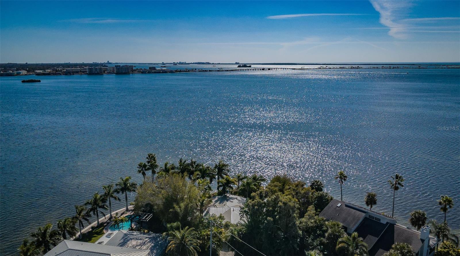 This modern, loft-like home is nestled at the end of the cul-de-sac on Ozona’s coveted Harbor Drive, commanding the tip of the peninsula. There are unparalleled views of water, sky, pool and lush tropical landscaping from every room, with complete privacy. This home was recreated for the modern world, with top of the line amenities and upgrades throughout. The exterior is an artful combination of coquina shell, Balinese wall carvings, travertine pavers, cypress soffits and an aluminum standing seam roof. Entering this bright and airy oasis, you’ll be impressed immediately with the walls of windows with wraparound views of St. Josephs Sound and the Gulf beyond. The vaulted ceilings and open floor plan combined with the cool terrazzo floors add to the serene atmosphere in the main space, which also has a custom three-sided gas fireplace. The gourmet kitchen is a chef’s dream, with a long waterfall design center island, quartz counters, and bespoke hard maple cabinets with frosted glass uppers and luminescent tile backsplash. The high-end appliances include a Sub-Zero refrigerator and wine cooler, Wolf induction cooktop, microwave drawer, built in oven and Fisher & Paykel dishwasher with dual drawers. Multiple undercounter sinks offer several prep and entertaining options. A convenient half bath with an Electrolux washer and dryer is located at the back of the kitchen with a door to the pool and grill. The primary suite is a fabulous retreat in its own right, with French doors leading directly to the patio and the water, and a custom California closet. The ultra-modern primary bath has vaulted ceilings, skylights, double undermount sinks with lighted, dimmable mirrors, quartz counters, and a soaking tub. Enter the master shower through enormous glass doors to a steam spa with twin rain shower heads and a spacious tile bench at one end. The must-see shower tile is custom made glass with a sterling silver backing. All bath fixtures throughout are Hans Grohe. A separate room houses a heated Toto Neorest bidet toilet. There is a separate guest bedroom and custom designed guest bath. The landscape is a tropical paradise, including a coconut palm that overhangs the stunning saltwater pebble tec pool and spa. The pool has multiple seating areas and LED lighting, a German engineered self-cleaning pop-up jet system, and can be controlled with an app. There is so much space to entertain and enjoy. There’s great grilling poolside or the primary patio dining area. Stroll the many travertine patios, walkways and driveway to enjoy the extensive plantings. Walk along the new seawall and watch the dolphins and glowing sunsets. This house has been reengineered from the ground up, with all new plumbing, HVAC and electric, spray foam insulation, and dimmable designer LED recessed and pendant lighting. Windows and doors are triple-paned and hurricane rated, including the custom frosted-glass garage door. The garage, which has a separate HVAC unit, doubles as a gym or additional guest space. New top-of-the-line aluminum standing seam roof is coated with Kynar finish. Harbor Drive is located near many marinas, restaurants and shopping in Ozona, Palm Harbor, Tarpon Springs and Clearwater. A short drive will take you to all the Tampa Bay area has to offer in beaches, attractions, sports and the Tampa International Airport. This turnkey home presents a once in a lifetime opportunity to experience the ultimate in waterfront living.