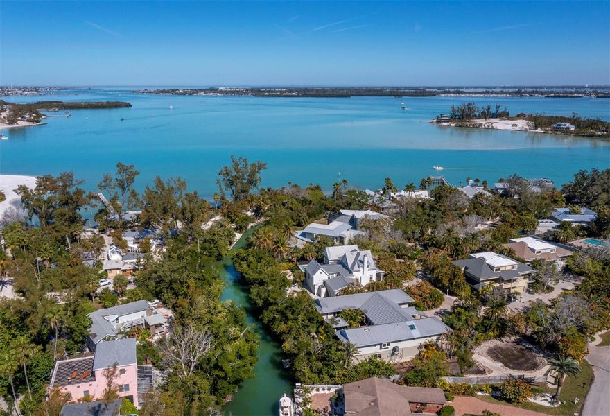 In a rich tropical waterfront setting on Longboat Key, this unique retreat lives like a modern treehouse while evoking a sense of peace, family and comfortable, easy island living. Tucked within the island’s native landscape along a natural bayou off Sarasota Bay, the property offers a rare opportunity to experience serene waterfront living surrounded by nature, with the Gulf’s azure waters and pristine beach access just moments away. Enjoy your private backyard dock and kayak launch or secure your boat on one of the deepwater slips on the open bay. Excellent fishing and bird watching await right outside your door in this remarkable natural habitat. The spacious home is anchored by a stunning great room with vaulted cedar ceilings and exposed beams. The home features a 40-by-9-foot sunroom with bar area and handcrafted art shelves, a dedicated library, an inviting family room and a separate private office with extensive built-in cabinetry, providing warmth and functionality. Extensive decking spans the front entry and wraps around an inner atrium courtyard for alfresco dining. An elevated cabana-style shaded area invites relaxation in sun and shade. The kitchen with center island is positioned for hosting memorable gatherings. The primary suite offers a full wall of windows overlooking the tranquil bayou, two walk-in closets and an additional wall of custom storage. The split floor plan provides a separate wing for guests, featuring two additional bedrooms and baths for convenient hosting. Each guest room offers private access to the outdoor decks and views of the tropical center atrium. Two garages accommodate up to four vehicles, boats, golf carts or paddleboards. Many of the furnishings are included. In Land’s End, an intimate gated community of just 12 residences, owners enjoy maintenance-free landscaping, a heated pool, tennis and pickleball courts, and convenient deepwater boat slips, all artfully tucked among the trees for privacy. From here, it is a short visit or golf cart ride to the captivating sandy Gulf beach or local favorites, including Shore Longboat Key, Mar Vista Dockside Restaurant and Whitney’s. The adjacent plaza also offers multiple popular waterfront cafes, boutique shops, Ventura’s restaurant, and 24/7 gym or Pilates studio. Enjoy mesmerizing sunsets on the Gulf or sunrises on the bay from this waterside community. This is a rare offering in today’s marketplace, capturing the allure of Old Florida living in one of the island’s treasured enclaves.