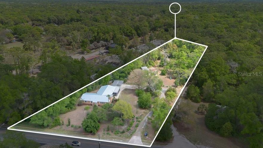 MUST SEE to really appreciate all this property has to offer on a private 2.5 acre lot !  Two homes on the property, 2 separate utility meters, rent one and live in other or use as a 2nd home for multifamily. Front home is large 5-bedroom custom home.   Additional Dwelling Unit (ADU) is 2 bedrooms 2 baths  remodeled and spacious with separate utilities, fenced in yard, shed and carport.  Main home has real hardwood floors throughout and  includes a formal living room with wood burning fireplace, formal dining room with built-in shelves, custom closets in bedrooms, large kitchen with gas oven and cooktop with wood cabinetry, crown moldings chair rails, laundry room, family room with French doors that open to the large screened enclosed porch, and a bonus room. Recent updates include: NEW gutters (2023), metal roof (2023), windows (2022), paver patio (2022), remodeled 2nd bathroom (2019), and whole house water filtration (2019). Located between the two homes is a large (20 x 30) storage / workshop with newer garage door and a (30 x 15) bay for boat or RV storage. Outside you’ll find a garden, playground, and your very own fruit orchard featuring a variety of trees! Don't miss out on this amazing property!