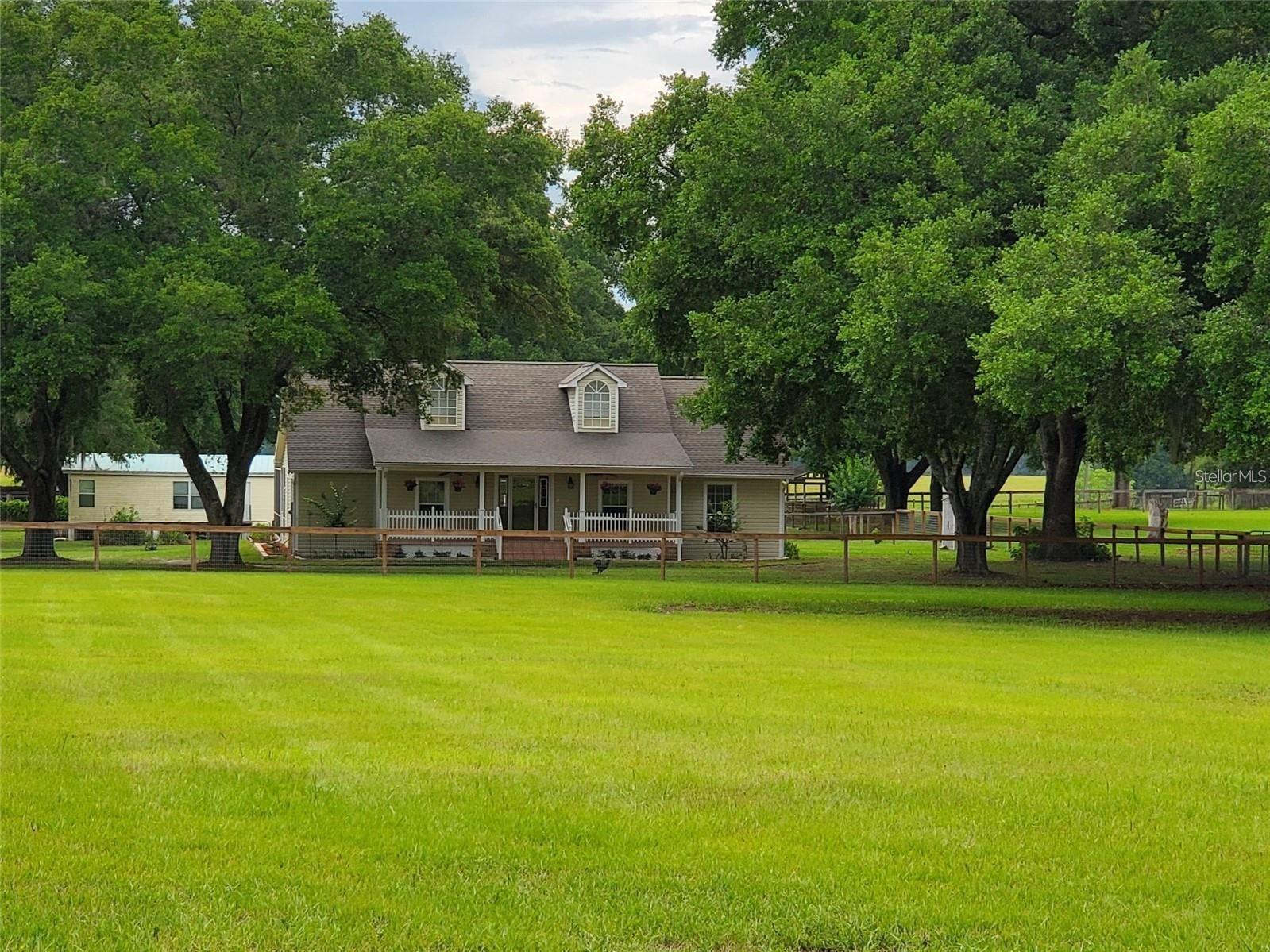 10 ACRES and 2 HOMES on beautiful fenced and crossed fenced, improved pasture with picturesque old southern oaks. Down the gravel, private drive to the custom built in 2002, C/B 2073 sq ft, 4 bedrooms, 2/1 bath main house. Step into the 37'x53' screened enclosed patio and take a dip on those hot days in the 10,000 gallon, saltwater pool and drift amongst the fountains. Entertaining family and guests in this open floor plan and the sit-down wrap around bar in the kitchen will make this house the place everyone gathers for all those special occasions or just because it is Saturday! 10-foot ceilings throughout this custom home! Formal dining room or great office space at the front of house. Lounge on the white railed front porch in rocking chairs with a cool beverage or coffee in the a.m. and watch your horses or cattle graze. A large master suite with walk-in closet and master bath offers double sinks, tub for soaking and separate shower. Use the second bedroom attached to the jack-and-jill bath as a dressing suite with the 2 additional large closets or perfect for the baby’s room. Split plan offers the space everyone in the household needs. Homes of Merrit (960 sq ft) doublewide mobile home is a 3 bedroom / 2 bath with a big covered rear porch. Great mother-in-law suite, winter guest cabin or income producing rental. Separate parking areas offer privacy for both homes. Covered 2 stall parking and attached shop with a new roof entirely on a concrete slab. RV/Horse trailer awning 15x40. Pastures are 4 board cross railed fenced in the front lending to the southern ranch appeal and the rest of the acreage is no-climb horse wire with top board. Run-in for those rainy days or convert to a stall. Pastures have nice, established bahai grass. Concrete block home with vinyl siding and aluminum soffits - no exterior painting! Dog pens. RV awning. One owner and maintained with pride! Many updates since built. Close to Ocala National Forest and all it has to offer.