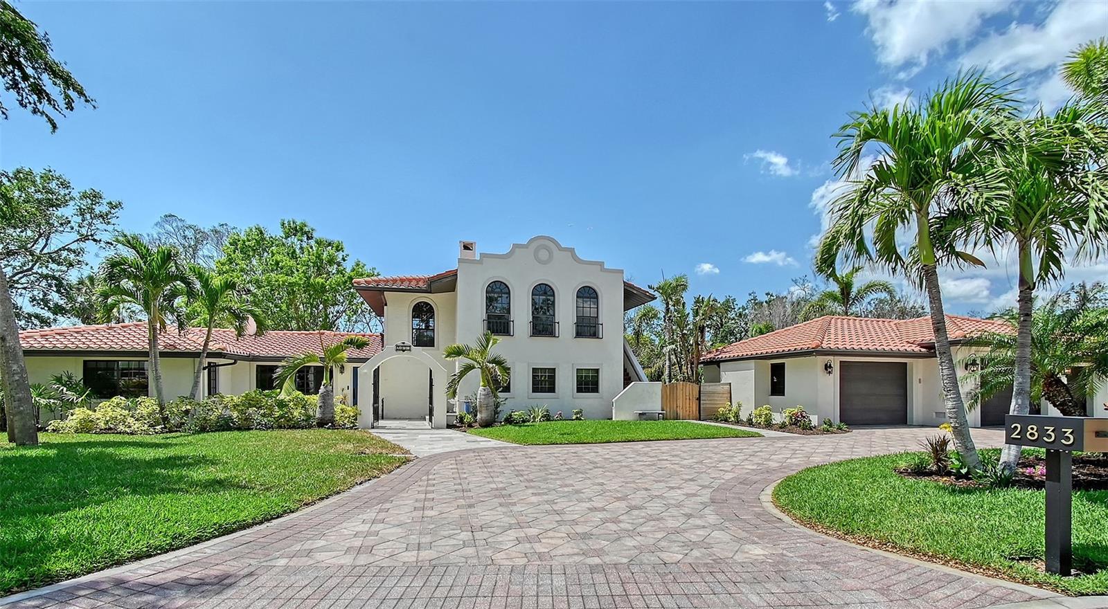 Welcome to this beautifully updated Indian Beach Sapphire Shores West of Trail residence, ideally located just steps from the Bay with quick access to downtown Sarasota, SRQ Airport, UTC Mall, and the white sands of Lido Beach. Nestled on a lushly landscaped half-acre lot, this smart home is a rare blend of comfort, elegance, and indoor-outdoor living. Offering 2,974 square feet of refined space, this 3-bedroom, 2.5-bath home features a spacious layout ideal for both everyday living and entertaining. The heart of the home is the expansive gourmet kitchen, appointed with Miele appliances, an oversized kitchen island with breakfast bar, wood-beam ceilings, and an open flow to flexible dining or family room space. The large living room is bathed in natural light from two large picture windows and a door to the back yard - perfect for seamless indoor-outdoor living. Bedroom 2 opens to a private screened porch through French doors — an inviting retreat for guests or family. Upstairs, the primary suite is a true sanctuary. Enjoy a cozy wood-burning fireplace, an open loft for a home office or den, and a private balcony with peek-a-boo views of Sarasota Bay sunsets. Step outside to discover an expansive shell stone pool deck with a heated pool, spa, and a shaded gazebo. Multiple areas for lounging and dining invite year-round entertaining in this private tropical haven. Additional features include an oversized, air-conditioned 3-car garage, brick paver circular drive with plenty of parking space, new interior paint, stylish plank tile flooring, and integrated smart home capabilities. This is a rare opportunity to own a thoughtfully designed and impeccably maintained home in one of Sarasota’s most desirable historic neighborhoods.