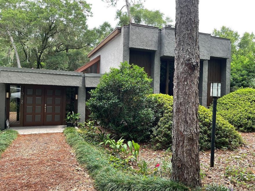 Came through Hurricane Ian with no problems! Move in Ready! Modern mid-twentieth century architectural style home designed by John DeLong and built by Delo Builders in 1977. This unique 3 story home is hidden from the street in a beautiful Florida hammock of Oaks and Pines. 3 bedrooms, 3 baths, double sided fireplace in living/family room, screened courtyard with Koi pond, separate bonus room with its own AC unit, wet bar,  and fireplace, lots of outside decking, attached 2 car garage/basement with lots of storage. Circular drive and extended driveway to garage located in the rear of the home.  All this on a half acre lot. Located on a cul d sac with walking and bicycle trails. ;Water: City