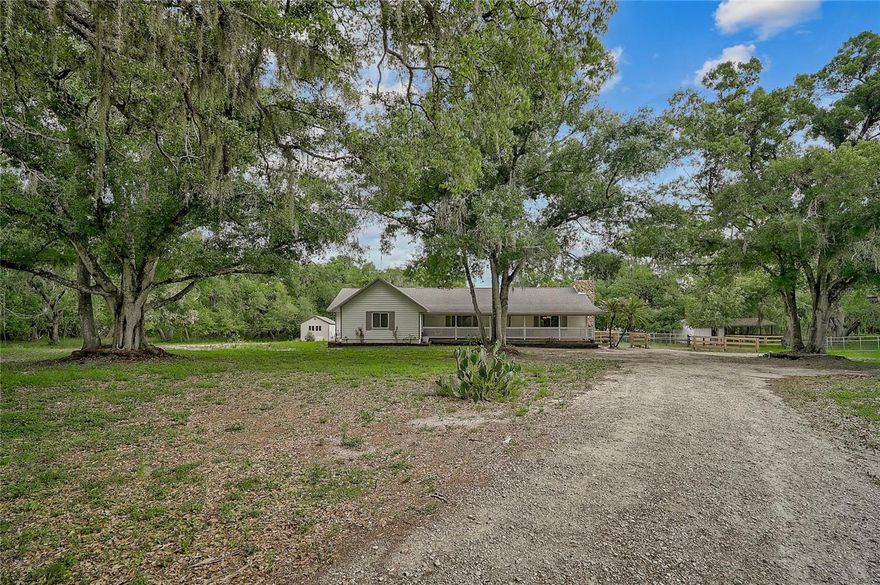 Rare 5-Acre East Bradenton Retreat with Updated Interiors & That Old Florida Setting! Welcome home to this expansive 5-acre East Bradenton retreat offering privacy, flexibility and beautifully updated living space in a peaceful Old Florida setting. Tucked beneath mature trees, this 3-bed, 2-bath home offers 2,345 square feet of living space, front and rear long covered porches, multiple fenced pastures, gated sections and the freedom of acreage living. Inside, the home opens to bright, refreshed living spaces with updated flooring, recessed lighting and a warm blend of modern finishes and rustic character. The kitchen has been beautifully updated with a large center island, abundant cabinetry, sleek countertops, stainless appliances, wall oven, cooktop and a stylish backsplash, creating a functional gathering space that connects easily to the main living area. Just off the kitchen, the step-down living area creates a warm and inviting space centered around a wood-burning stone fireplace. Rich wood paneling across the ceiling adds character, texture and rustic charm, beautifully balancing the home’s modern updates. The primary suite offers a spacious bedroom, impressive updated bathroom and large organized walk-in closet with built-in shelving and hanging space. The bathroom features a freestanding soaking tub, glass-enclosed shower, full-height tile detail and dual vanity. Additional bedrooms provide flexibility for family, guests, work-from-home space or hobbies. The oversized utility room adds incredible everyday function with a sink, cabinetry, counter space, refrigerator, oversized pantry and additional storage closet. Whether used for laundry, storage, overflow prep space or keeping everyday essentials organized, this room is a standout feature that makes the home live even better. Outside, the 5-acre property offers multiple fenced pastures, open yard areas, mature trees, gates and a barn with a storage room and covered pad. Whether you envision animals, gardening, hobby farming, equipment storage, recreation or future improvements, the land gives you space to create the lifestyle you want. The location adds even more appeal, giving you the quiet feel of acreage living while keeping you close to everyday convenience. Waterline Rd offers a peaceful East Bradenton setting near the growing Lakewood Ranch and Parrish corridors, with access to shopping, dining, schools, parks, medical facilities and major roadways. From here, you are also within reach of downtown Bradenton, Sarasota, St. Petersburg, Tampa and the beaches of Florida’s Gulf Coast. With its rare combination of land, privacy, updated interiors, fenced pastures, functional outbuildings and convenient location, this Waterline Rd property offers a lifestyle that is increasingly hard to find!