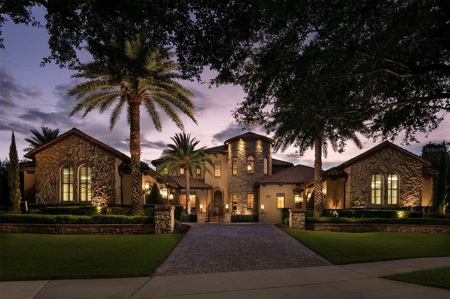 Located in Grosvenor Village within Keene’s Pointe, this estate overlooks a pond and the Tibet-Butler Preserve. Built by Stonebridge Homes and updated with interior design by Goehring & Morgan, the home includes professionally designed spaces by Angela Neel Interiors, lighting from Fine Art Handcrafted Lighting, and finishes including Emperador marble and Venetian plaster. The floor plan features a formal living room with a groin-vault ceiling leading to a central kitchen with Busby cabinetry, Emperador marble countertops, and two islands. Appliances include Miele steam oven, gas cooktop, wall oven, warming drawer, dishwashers, and a Sub-Zero refrigerator. The kitchen connects to the family room, dining area, and elevator lobby and is located near a home gym equipped with Cybex Eagle equipment. The primary suite includes a sitting area with fireplace, Busby built-in wet bar, wardrobe storage, and a bath with dual vanities, soaking tub, and walk-through shower. Additional interior features include a home office with wood flooring and display cabinetry, spiral staircase to the upper level, game room with kitchen, walk-in closet, and attic access, a laundry room, and a four-car split garage. Outdoor amenities include a covered lanai with fireplace, seating area, and sunset views over the pond and conservation area. The outdoor space also features a summer kitchen with gas grill and refrigerator, heated saltwater pool with sun shelf, travertine pool deck, and fire bowls with marble column accents. Sold fully furnished.