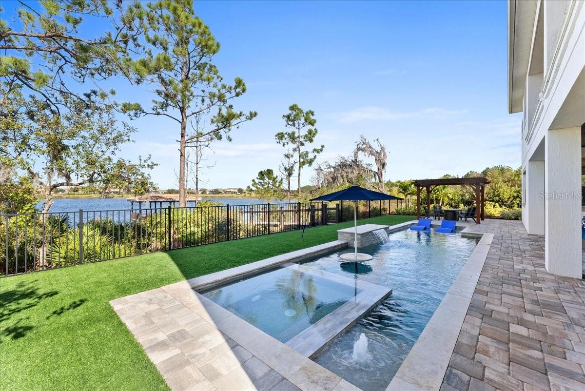 Stunning Luxury Lake Front Home located on a cul-de-sac and a corner lot minutes from Disney World in the sought-after community of Horizon West. As you walk through the large double front doors you will be greeted by an open concept floor plan, tall ceilings, lots of natural light, expansive windows and glass sliding doors opening up to a backyard paradise with beautiful lake views. This approximate 5,000 sq ft, 5 bedroom, 5 bath home boasts a gourmet Kitchen with upgraded large cabinets, soft close doors and drawers, natural gas stove, oversized island, buffet, walk-in pantry and glass wine room, which are all perfect for entertaining. The Family Room has a feature wall with an Electric Fireplace. Off of the family room through the double sliding barn doors you enter the theater room with a high definition projector and automated screen with movie theater sound. Also on the first floor is a guest suite with walk-in closet and full bath, a large flex room that can be used for an office, gym, playroom, game room, the possibilities are endless and a 2nd full bath to complete the first floor. As you walk up the stairs you will be wowed by the large loft, with double glass sliding doors expanding the length of the wall featuring sweeping views of the lake. The loft has custom cabinets with a butcher block countertop, drink drawers and 3 TV’s above to watch all your sporting events at once. Step onto the oversized covered balcony with breathtaking sunsets and enjoy the serenity of the lake and back yard. Accessible from each side of the balcony are a bedroom with full bath and on the other side a spacious master bedroom both sharing magnificent views of the lake. From the Master bedroom enter through a sliding barn door to a large Master spa featuring a free standing bathtub, oversized shower with bench seating, 3 upgraded shower heads, double sinks and towel closet. Through the master bath enter the walk-in closet with floor to ceiling built-in features conveniently attached to the laundry room with granite countertops, cabinets, shelving, storage and a sink. There are 2 more bedrooms with another full bath and additional storage closet. The back yard Oasis features a dock with a boat lift, electricity, water, and rail lighting. This maintenance free fenced in back yard has turf, luscious plants and trees. Sit under the covered lanai gazing at the lake with a custom-built outdoor kitchen, with outdoor speakers, television and an expanding patio that continues with a pergola and fireplace. The Natural gas heated pool features an over-sized hot tub, waterfall, bubbler, bench seating, sun shelf and a built-in table with umbrella. In addition, the pool has auto fill and drain, lighting and it is all controlled by your phone. This smart home has a security system, video doorbell, Lutron lights, landscape lighting front and back of the home, a Sonos system with speakers throughout, control 4 and a media closet. The newly built home offers luxurious finishes, premium building materials and offers additional features such as plantation shutters, a water filtration system with reverse osmosis for drinking water, trey ceilings in the family room and master bath, large base boards, solid doors, upgraded tile plank flooring on the first floor, hard wood on the 2nd floor and an oversized 3 car garage with overhead storage and a Tesla
charger. This home has it all and is move in ready.