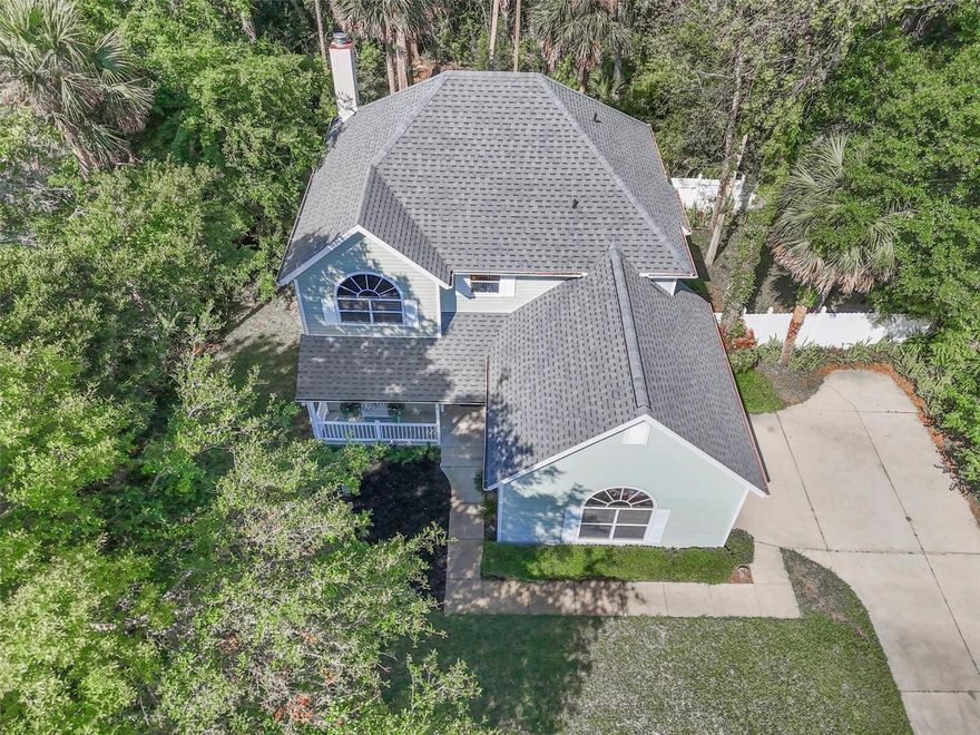 Tucked beneath a canopy of mature trees in the gated community of Fairchild Oaks, this home offers a rare blend of privacy, natural light, and everyday livability. Positioned beside a vacant, unbuildable lot and backing to a wooded preserve, the setting feels incredibly secluded—you truly don’t see neighbors from the back—creating a peaceful, treehouse-like atmosphere surrounded by greenery. The inviting front porch with a sitting area sets the tone, while the fully fenced side yard is lined with blooming jasmine that fills the air with an amazing fragrance. Out back, the oversized screened-in lanai—with both covered and open sections—becomes a true extension of the home, perfect for relaxing or entertaining year-round. Inside, the space is bright and open with soaring ceilings, large windows, and French doors that connect the living area to the outdoors, bringing in natural light from every angle. The kitchen flows easily into the main living space and dining area, while a convenient half bath and laundry room sit just off the garage. Upstairs, all three bedrooms are generously sized and filled with light, including a spacious primary suite featuring a large walk-in closet with built-ins and additional attic access. The home also offers a long driveway with plenty of parking, abundant storage throughout, a roof replaced within the last 3 years, and an AC and water heater both within the last 4 years, along with a termite bond for added peace of mind. Located in a low HOA gated community just minutes from Flagler Beach, shopping, and dining, this home delivers the perfect combination of comfort, privacy, and Florida living.