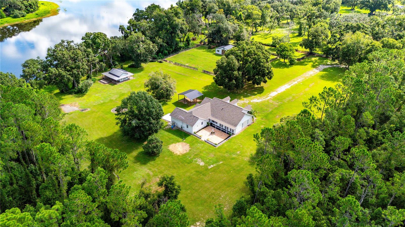 One or more photos are virtually staged. Welcome to 34961 Easterling Road in the heart of Dade City, where country living meets timeless design. Tucked behind a private gated entry, this 8-acre horse property offers the ultimate blend of privacy, elegance, and functionality with over 570 feet of pristine lake frontage. The sweeping views are picturesque and serene, with no neighbors in sight, just rolling countryside, mature trees, and wide-open skies.
The main residence offers nearly 3,000 sq. ft. of living space, featuring 3 bedrooms and 3 full baths. One oversized bedroom can easily be converted back into a 4th bedroom, home office, or flex space to suit your needs. Throughout the home, you’ll find a modern farmhouse style accented by coffered ceilings, custom molding, and designer wall details that add warmth and charm to every room. The spacious living area boasts a striking electric fireplace, while the open, flex floor plan provides plenty of room to entertain or relax in comfort.
The kitchen is a true showpiece, designed for both beauty and function. Highlights include a massive center island, granite countertops, double built-in ovens, a smooth cooktop, farmhouse-style sink, and an expansive walk-in pantry. Whether hosting large gatherings or enjoying everyday meals, this kitchen is the perfect heart of the home.
The master suite is equally impressive, offering two walk-in closets and a luxurious ensuite bath with dual vanities, a jetted soaking tub, and a separate walk-in shower. A large family/bonus room with 3 sets of French doors, open to a brick-paved courtyard with a beautiful fountain centerpiece, creating a seamless transition between indoor and outdoor living.
Beyond the home, the property continues to impress. A charming “casita” with a wrap-around porch overlooks the private lake, an incredible setting for weddings, family events, or simply soaking in the peaceful lake views and wildlife. For equestrian lovers, a 4-stall horse barn and open acreage provide ample space for horses or livestock. The land is enriched with papaya, walnut, and pomegranate trees, adding natural beauty and functionality.
With a new roof installed in 2021, this estate offers peace of mind alongside its many rare features. Properties of this caliber, with acreage, lake frontage, and modern updates, are rarely available.
Location is another highlight. Just 5 minutes away you’ll find Lake Jovita Golf & Country Club, offering championship courses, dining, and social amenities. I-75 is less than 10 minutes from your gate, providing quick access to Tampa, Wesley Chapel, Brooksville and Orlando. And with new shopping and restaurants on the way along Hwy 52, you’re perfectly positioned to enjoy both the peace of country life and the convenience of modern growth.
34961 Easterling Road is more than just a home; it’s a lifestyle. Whether you’re seeking a private retreat, an entertainer’s paradise, or the perfect horse property, this Dade City treasure delivers it all.