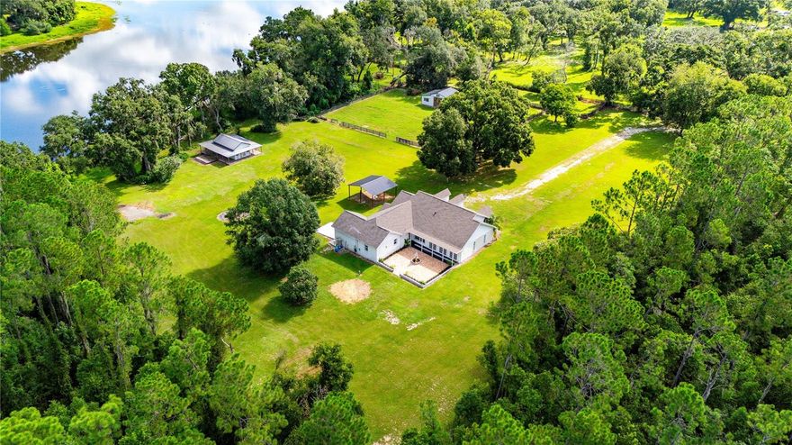 One or more photos are virtually staged. Welcome to 34961 Easterling Road in the heart of Dade City, where country living meets timeless design. Tucked behind a private gated entry, this 8-acre horse property offers the ultimate blend of privacy, elegance, and functionality with over 570 feet of pristine lake frontage. The sweeping views are picturesque and serene, with no neighbors in sight, just rolling countryside, mature trees, and wide-open skies.
The main residence offers nearly 3,000 sq. ft. of living space, featuring 3 bedrooms and 3 full baths. One oversized bedroom can easily be converted back into a 4th bedroom, home office, or flex space to suit your needs. Throughout the home, you’ll find a modern farmhouse style accented by coffered ceilings, custom molding, and designer wall details that add warmth and charm to every room. The spacious living area boasts a striking electric fireplace, while the open, flex floor plan provides plenty of room to entertain or relax in comfort.
The kitchen is a true showpiece, designed for both beauty and function. Highlights include a massive center island, granite countertops, double built-in ovens, a smooth cooktop, farmhouse-style sink, and an expansive walk-in pantry. Whether hosting large gatherings or enjoying everyday meals, this kitchen is the perfect heart of the home.
The master suite is equally impressive, offering two walk-in closets and a luxurious ensuite bath with dual vanities, a jetted soaking tub, and a separate walk-in shower. A large family/bonus room with 3 sets of French doors, open to a brick-paved courtyard with a beautiful fountain centerpiece, creating a seamless transition between indoor and outdoor living.
Beyond the home, the property continues to impress. A charming “casita” with a wrap-around porch overlooks the private lake, an incredible setting for weddings, family events, or simply soaking in the peaceful lake views and wildlife. For equestrian lovers, a 4-stall horse barn and open acreage provide ample space for horses or livestock. The land is enriched with papaya, walnut, and pomegranate trees, adding natural beauty and functionality.
With a new roof installed in 2021, this estate offers peace of mind alongside its many rare features. Properties of this caliber, with acreage, lake frontage, and modern updates, are rarely available.

Location is another highlight. Just 5 minutes away you’ll find Lake Jovita Golf & Country Club, offering championship courses, dining, and social amenities. I-75 is less than 10 minutes from your gate, providing quick access to Tampa, Wesley Chapel, Brooksville and Orlando. And with new shopping and restaurants on the way along Hwy 52, you’re perfectly positioned to enjoy both the peace of country life and the convenience of modern growth.

34961 Easterling Road is more than just a home; it’s a lifestyle. Whether you’re seeking a private retreat, an entertainer’s paradise, or the perfect horse property, this Dade City treasure delivers it all.