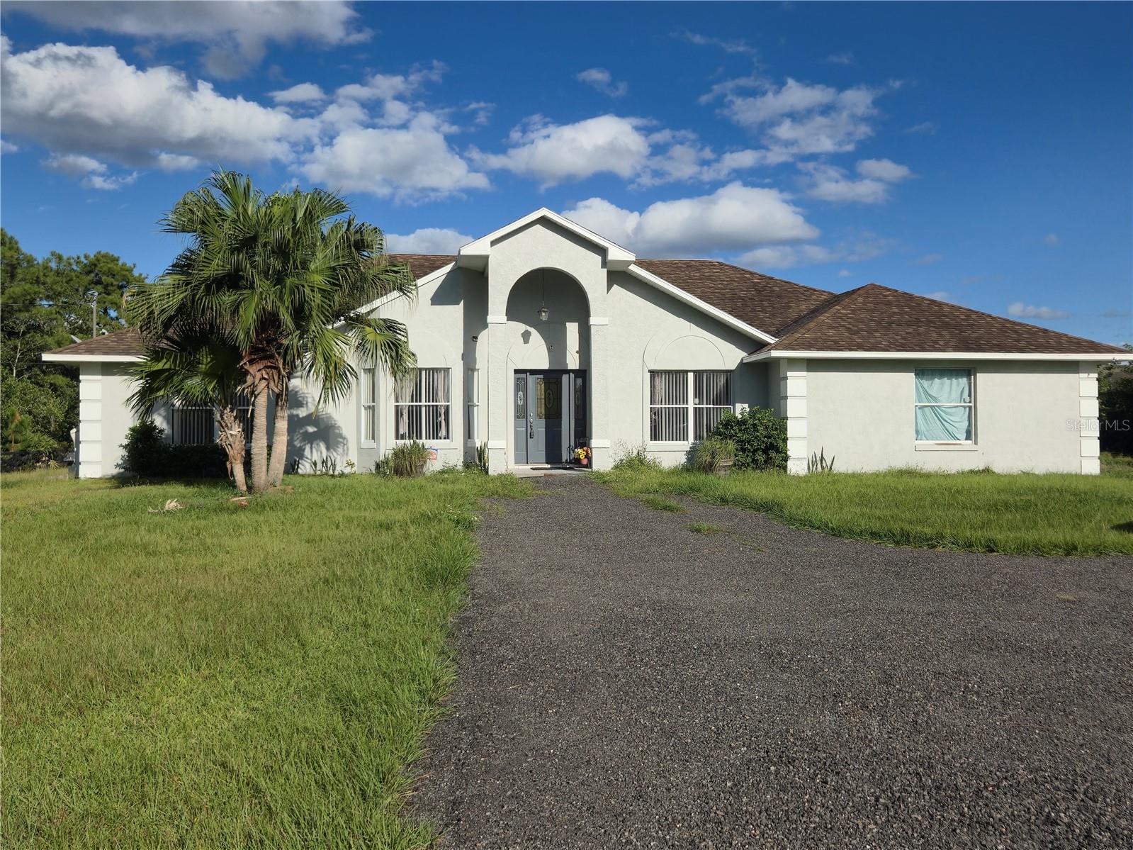 Peaceful Country Living with a Pool on 4.8 Acres – NO HOA! Experience the perfect blend of privacy, space, and comfort with this beautiful 4-bedroom, 2-bathroom pool home in the desirable Bay Lake Ranch community. Step inside and enjoy an open, welcoming layout featuring tile floors throughout the main living areas and bedrooms. The kitchen boasts GRANITE countertops, a wraparound bar, and a cozy breakfast nook overlooking the sparkling pool — perfect for your morning coffee or tea. The living room features a wood-burning fireplace and sliding doors that lead directly to the pool deck, ideal for outdoor grilling and entertaining. The primary suite offers true relaxation with wood-grain tile flooring, private pool access, and an ensuite bathroom complete with dual sinks, a private water closet and a large glassed-in shower featuring a rain shower head giving you a luxurious shower experience. There is a very large walk-in closet ready for your dream organization setup. Each bedroom provides ample space and natural light. The fourth bedroom and the 2nd bathroom have direct pool access, making it convenient for guests after a refreshing swim. Two versatile bonus rooms at the front of the home provide flexibility for a home office, formal dining room, game room, or library — the possibilities are endless. The laundry room is generously sized and includes a soaker sink, perfect for rinsing off swimsuits or handling extra dirty clothes. Outside, enjoy your fenced backyard, saltwater softener system, and private gated entry with a paved driveway leading all the way to the front door and side-entry garage for added curb appeal and privacy. Additional highlights include: Exterior re-painted in 2024, Well and septic (no monthly water bills!), private mailbox and the land is zoned for a guest house to be built on the property. Prime Location: Only 30 minutes to Lake Nona Medical City, 45 minutes to Orlando International Airport, and less than 1 hour to Port Canaveral, Cocoa Beach, Melbourne Beach, Universal Studios, and Disney. Multiple golf courses, restaurants, shopping and grocery stores are just a short drive away! Don’t miss this rare opportunity to own acreage with a pool and NO HOA in Bay Lake Ranch. Call today to schedule your private showing — your forever home awaits!