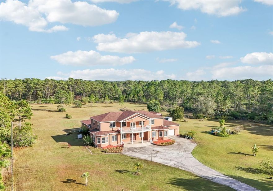 One or more photo(s) has been virtually staged. Dreams do come true! Welcome to your private slice of paradise in Wedgefield! This impressive custom-built estate offers over 5,000 square feet of living space with 6 bedrooms and 6 bathrooms, beautifully set on 4.77 acres and zoned A-2, so you can bring your horses, goats, chickens and more. Built in 2004 and well-maintained, this property blends peaceful country living with modern convenience and community amenities, including an 18-hole golf course, playgrounds, sports courts and nearby Hal Scott Preserve for hiking, biking and nature lovers. A 5-foot wrought iron fence spans the 360-foot front yard with a 20-foot wrought iron electric gate and pedestrian gates on either side, while the rest of the property is enclosed with 5-foot wire fencing- ideal for animals and added privacy. The enormous front and back yards are perfect for play, gardening, entertaining and enjoying the quiet setting, and the 288 sq. ft. Tuff Shed provides excellent additional storage. Step up to the Shark Coating front porch and through the double-door entry into a grand foyer that sets the tone for the rest of the home. Gorgeous inlaid porcelain tile flows throughout the first-floor living areas, and arched vaulted ceilings add volume and elegance. To one side of the foyer is a welcoming sitting room, and to the other, a formal dining area ready for large gatherings. The spacious, open kitchen anchors the main level with granite countertops, a granite breakfast bar, recessed lighting, abundant cabinetry and a huge walk-in pantry. The open concept layout connects all the spaces, giving you endless options for arranging living, dining and entertaining spaces to suit your lifestyle. On one side of the main floor you will find a guest bedroom with its own private bathroom featuring a Jacuzzi tub with shower - great for visiting guests or multi-generational living. The opposite side of the home hosts two individual office spaces, each with its own exterior entrance and one with a half bath, creating an ideal setup for remote work, home-based business, studio or hobby spaces. The main floor primary suite is a true retreat, complete with a tranquil sitting area and separate dual walk-in closets. The expansive primary bath offers a glass-enclosed shower, luxurious Jacuzzi garden tub and dual vanities, giving you a spa-like experience at home. French doors from the main living area open out to an approximately 1,100 sq. ft. screened lanai with porcelain tile flooring and a peaceful forest view. This impressive outdoor living area includes counter space with cabinets, a sink and a convenient half bath - perfect for hosting parties, enjoying quiet mornings with coffee, or relaxing after a long day without ever leaving your property. Up the grand curved staircase, a loft area opens to a balcony overlooking the front yard, giving you yet another beautiful space to relax or gather. Four additional bedrooms extend off the loft, two on each side, and each pair of bedrooms is served by a bathroom with a Jacuzzi tub and shower. One of the upstairs bedrooms features its own private sunroom, adding even more flexible living space for a reading nook, playroom, workout area or creative studio. This home is truly impressive - offering space, serenity and versatility inside and out! Come experience the peaceful setting and spectacular location for yourself. Call today to schedule your private showing an ASK US ABOUT THE ASSUMABLE VA LOAN or LENDER PROVIDED RATE BUY-DOWN CREDIT!