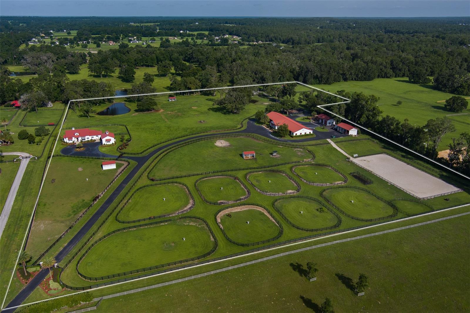 WOW! This amazing 24.9 acre farm is almost too good to be true! It's just down the street from the World Equestrian Center in the horse community of Wellington. This farm is truly a horse enthusiast's paradise. It begins with a beautifully landscaped gated entrance, and contains board-fencing throughout, multiple paddocks, an arena, auto-waterers, shade sheds, and plenty of lush green pastures. The custom 24-stall show barn features block stalls, tongue and groove ceiling with arched rafters, laundry room, full bath, office, tack room, fly spray, and wash racks. A 2-bay storage building provides for safe storage, and also contains a lovely 1 BR/1BA fully equipped apartment. There is also a 4 bay pole barn for hay, shavings, tools, and equipment. The exquisite 2021 home is making its debut on the market. It has an open floor plan, high ceilings, fireplace, sleek and modern island kitchen, and tons of windows for an open and airy atmosphere, plus wonderful views in every direction. There is a covered patio with grilling and dining areas, as well as an open patio with seating that overlooks the pastures and ponds beyond. There is also a fantastic entertaining area near the apartment and barn featuring a pergola, full kitchen, seating, and firepit.