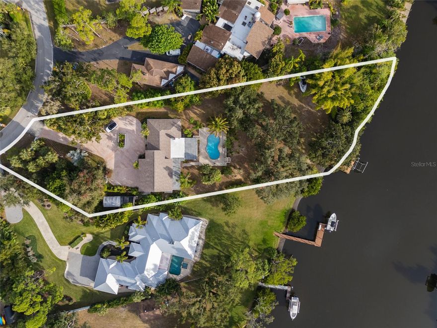 Imagine pulling up to this hidden waterfront treasure on a quiet Sarasota street, where a long, winding paver driveway curves gracefully through a canopy of majestic mature oaks, welcoming you to a sprawling 1.15-acre lot with 130 feet of prime frontage along the serene waters of Phillippi Creek. Elevated safely in Flood Zone X (no flood insurance required) and crowned with a brand-new 2024 roof, this property feels like your own private Old Florida estate from the moment you arrive.
Step out and take in the east-facing oasis: a gently sloping, oak-shaded yard that offers complete natural privacy, leading down to the water’s edge. Relax on the expansive covered porch with sweeping views of the creek, cool off in the freshly resurfaced 2025 pool, or slip through the convenient second porch—complete with ceiling fan—right off the pool bathroom and laundry area. It’s the perfect spot for drying off after a swim or enjoying a quiet breeze.
The true magic lies in the irreplaceable waterfront lifestyle. An expansive dock with a charming gazebo and boat lift awaits your adventures, providing direct access to protected waters, the Intracoastal Waterway, and the Gulf of Mexico. There’s even a dedicated kayak launch, so you can choose your pace—whether powering out for a day on the open water or quietly paddling along the scenic creek.
Best of all, this generous 1.15-acre parcel comes with no HOA and no deed restrictions, giving you ultimate freedom to truly live the Florida lifestyle—park your boats, add whatever suits your vision, or simply preserve the natural beauty just as it is.
Step inside the 1956 residence, and you’ll find more than 3,800 square feet under roof brimming with authentic character and endless potential. Oversized windows flood the open, flowing layout with natural light and breathtaking water views from nearly every room. High soaring ceilings create an airy feel, while a cozy fireplace invites quiet evenings at home.
The thoughtful design includes 4 bedrooms and 3 bathrooms, with the expansive upstairs primary retreat offering panoramic vistas. Currently divided into two large rooms by a non-structural faux wall, it’s a blank canvas ready to be reconfigured into an epic primary suite with a luxurious ensuite and generous walk-in closet.
All of this is just minutes from Siesta Key’s world-famous beaches, vibrant downtown Sarasota, top-rated schools, shopping, and dining—yet feels worlds away in its peaceful, private setting. This rare waterfront gem is ready for your personal touch, blending Old Florida charm with the opportunity to create your custom modern masterpiece. Schedule your private showing today!