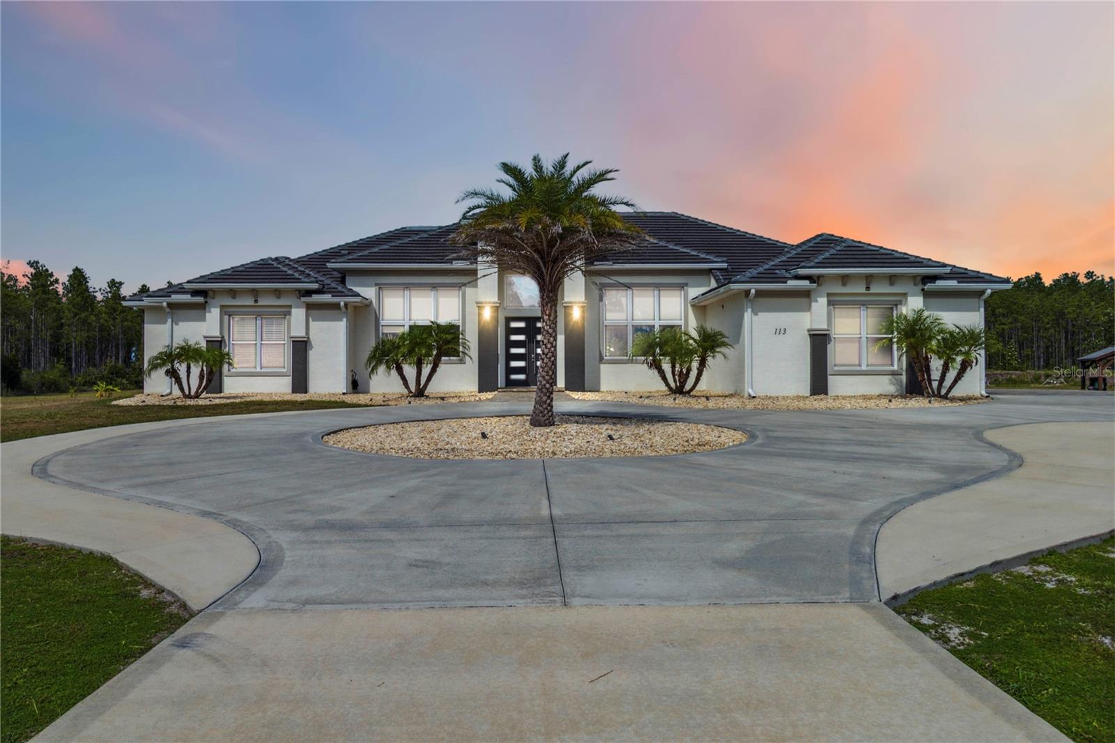 Experience refined Florida living in this one-of-a-kind custom estate, built in 2021 as a signature custom home by by owners through Olsen Homes. Set on nearly 11 private acres within the exclusive gated community of Sweetwater Estates, this property offers unmatched space, privacy, luxury, and added security. Constructed with solid block and topped with a durable tile roof, this home offers peace of mind and lasting value for years to come. Inside, you’ll find soaring 11’ ceilings throughout and a striking 15’ vaulted ceiling in the kitchen and living area. Every inch is finished with imported 24x48 Italian porcelain tile, including floor-to-ceiling tiled showers in all bathrooms.
This expansive 5-bedroom, 3.5-bath home includes walk-in closets in every bedroom, two additional hallway closets, and a completely separate private guest suite with its own entrance, cassette HVAC, kitchenette, and alarm pad, perfect for multi-generational living, long-term guests, or potential rental income.
The gourmet kitchen is a chef’s dream, fully equipped with top-of-the-line Thermador stainless steel appliances: built-in column refrigerator and freezer, double ovens, wine cooler, espresso machine, induction cooktop with pot filler, drawer microwave, dual dishwashers, and custom cabinetry topped with sleek white quartz. A spacious walk-in pantry adds function to the designer finish.
For the ultimate entertaining experience, six pocket doors along one full wall of the main living and kitchen area bilaterally open to the resort-style outdoor space—creating a seamless indoor-outdoor flow that’s perfect for hosting gatherings. The 34x14 heated infinity pool with UV sanitizer, 14x5 sundeck, and 10x10 infinity spa with 8 jets overlook a peaceful pond with fountain and sweeping private acreage. The pool and spa can be heated using either the home’s separate solar heat pump system or an underground 500-gallon propane tank, offering flexibility and efficiency. Outdoor amenities include a full kitchen with stainless gas grill, rotisserie charcoal grill, wood-fired pizza oven, quartz bar seating for 8, firepit, outdoor shower, four ceiling fans, and pre-wiring for a projector and TVs. Pool furniture is included.
Additional highlights include a whole-house reverse osmosis water filtration system with UV sterilization,, solar panels with batteries backup, 3-car garage, electric gate-ready connections, a private shooting range, and an expansive screened garden with metal raised beds. This is a rare opportunity to own a luxurious, turnkey estate where modern design meets peaceful, private living.
Schedule your private tour today! This luxurious property in the gated Sweetwater Estates community is truly one-of-a-kind and not to be missed.
