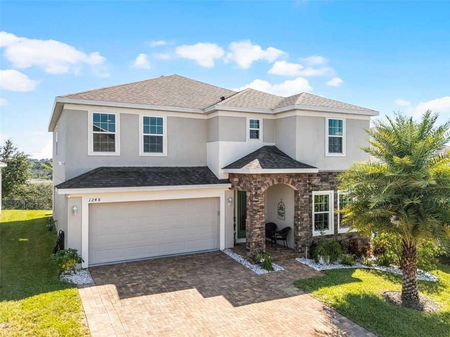 **Welcome to 1248 Cavender Creek Road!** This beautifully maintained 5-bedroom, 3-bathroom single-family home is nestled in the highly sought-after Ardmore Reserve community in Minneola, Florida. Ideally located just 30 miles west of Orlando and about 90 minutes from Tampa, the home offers easy access to world-famous theme parks and attractions. Plus, with the Florida Turnpike only five minutes away, commuting is incredibly convenient. Built in 2020, this residence features stunning curb appeal with stacked stone accents, a glass inset front door, and an extended paved permeable driveway. Inside, the home is meticulously kept and features tile flooring throughout the downstairs main living areas, luxury vinyl plank flooring in the front great room and staircase, and carpet in the downstairs bedroom. The elegant staircase, enhanced with unique vinyl plank design work, adds a distinctive touch of style. Step into a bright, open-concept interior designed for both comfort and sophistication. The modern kitchen is a chef’s dream, complete with a gas stove, 42-inch cabinets, quartz countertops, a generously sized island with detailed woodwork, and a convenient drop zone area—perfect for unloading groceries with ease. Stylish pendant lighting and updated stainless steel appliances enhance both beauty and functionality. On the main floor, a versatile flex space offers endless possibilities—ideal for a home office, formal living area, or creative studio. Unique woodwork throughout the foyer, kitchen, living room, and guest bedroom   adds charm and character you won’t find elsewhere. This home features a bedroom  and bathroom downstairs that is perfect for extended family or guests for ultimate privacy.  Upstairs, a spacious loft/game room offers the perfect retreat for a home gym, man cave, or entertainment zone, it also includes three generously sized bedrooms and a luxurious primary suite , lastly there is Luxury vinyl plank floor throughout the upstairs minus the 3 bedrooms which have carpet  and bathroom which feature tile.  The primary bathroom is a spa-like retreat, showcasing quartz countertops, a beautifully remodeled walk-in shower with floor-to-ceiling tile and a sleek glass slider door, as well as a spacious walk-in closet. The primary bedroom is generously sized and features luxury vinyl flooring and added recessed lighting. The ensuite bathroom offers a his-and-hers vanity with quartz countertops, an oversized closet, and a stunningly tiled shower that exudes elegance and style—sure to impress.The garage is impeccably maintained, boasting durable and stylish epoxy flooring along with additional storage space behind a charming barn door.Step outside into your own private tropical oasis. The extended, screened-in lanai provides breathtaking views of **Plum Lake**, making it the perfect place to relax and soak in the Florida lifestyle.